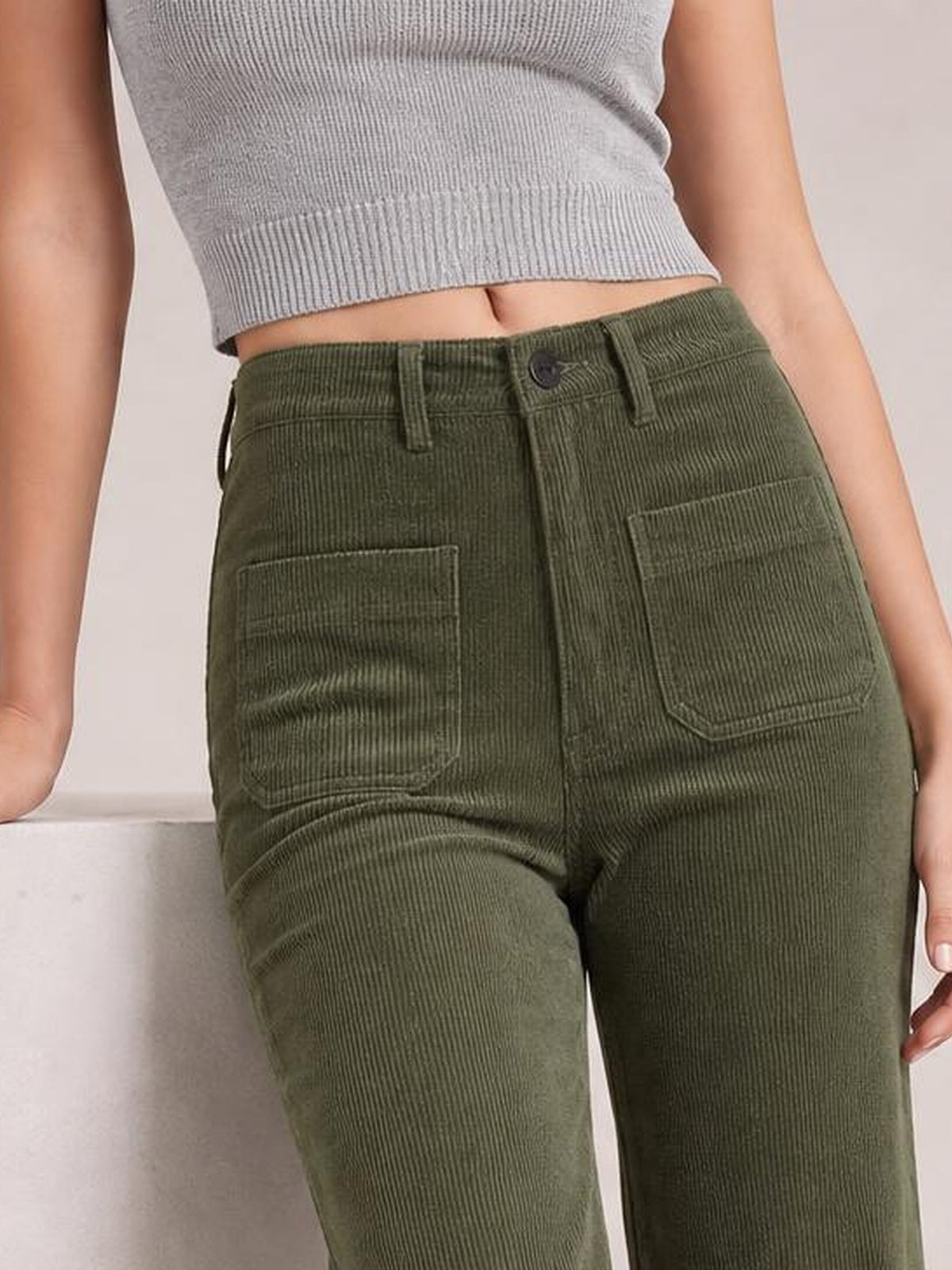 Model wears olive green high-waist corduroy pants with a straight-leg silhouette, belt loops, button closure, and square patch pockets.
