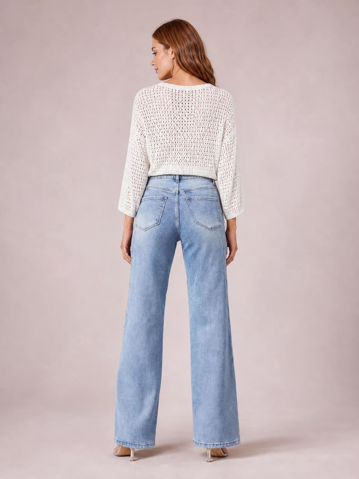 Model viewed from behind wears washed light blue high-waist straight jeans with belt loops, back pockets, and a full-length silhouette.