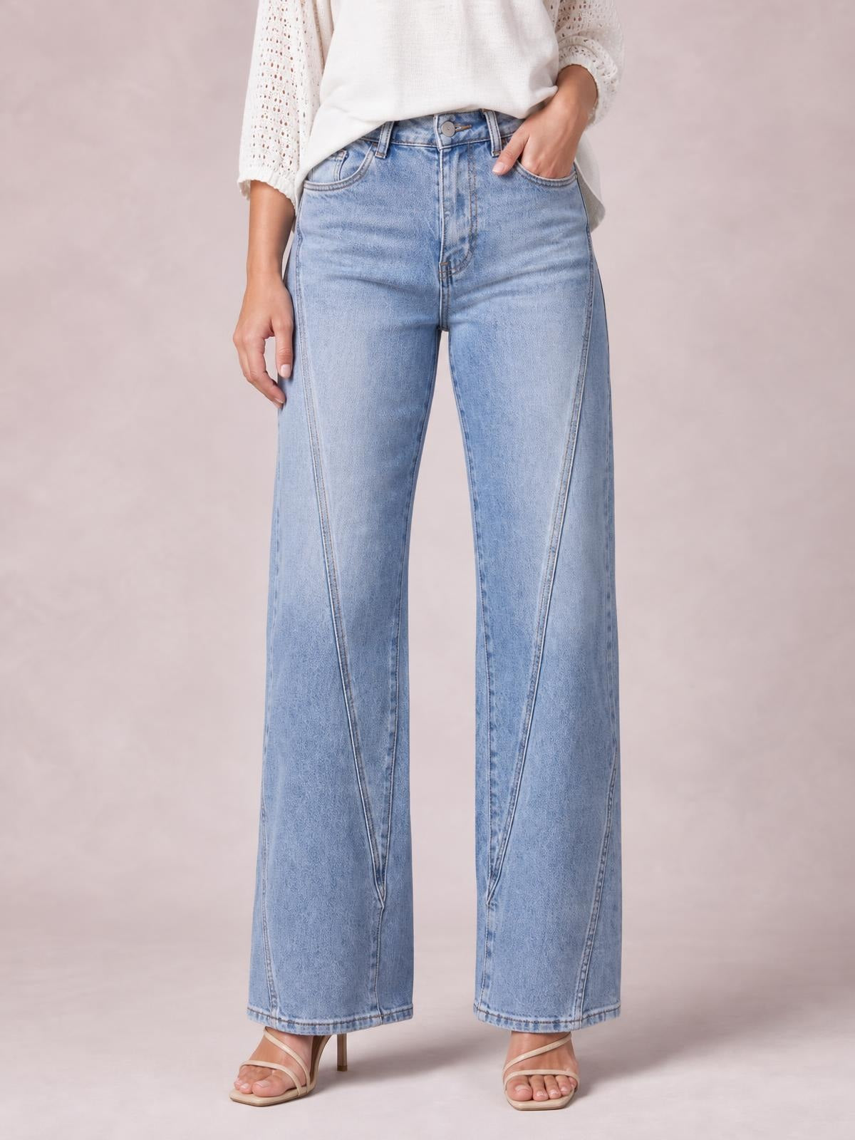 Model wearing light-wash high-waist straight-leg jeans with front pockets, belt loops, button closure, and visible seam detailing, shown standing with one hand in a pocket.