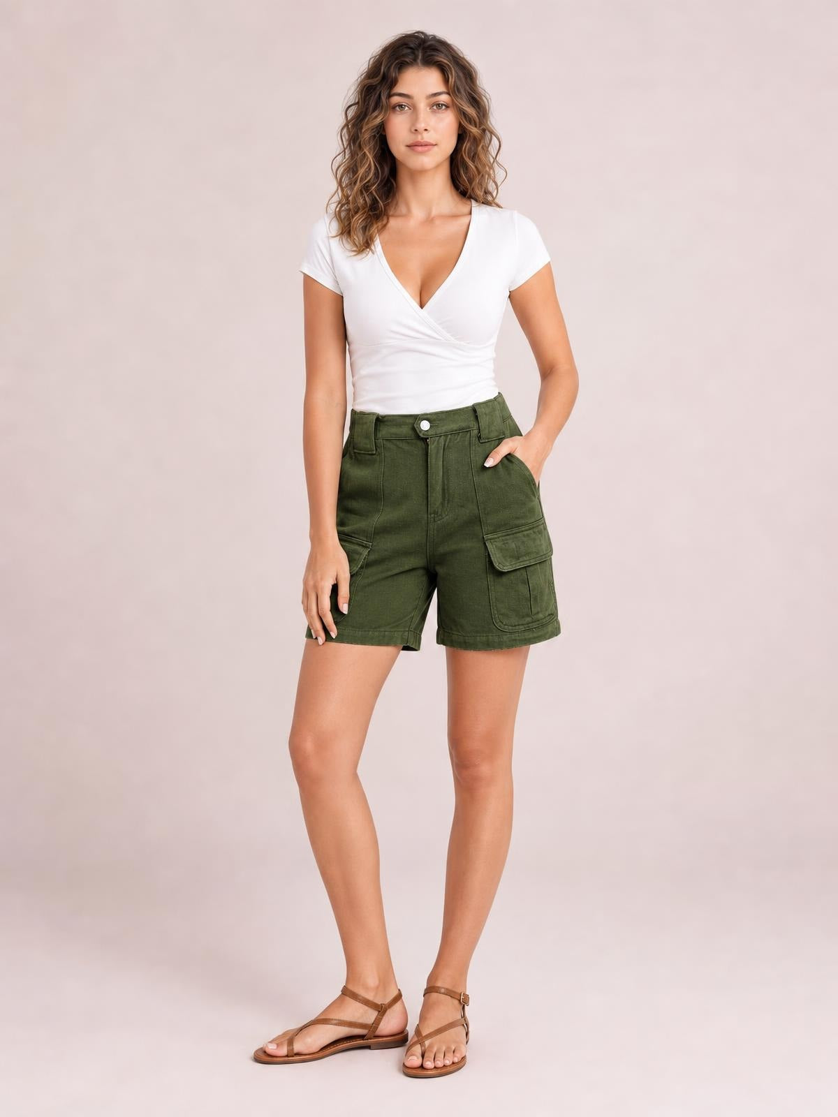 A model poses in olive green high-waist shorts with a structured straight-leg silhouette, belt loops, front pockets, and large flap cargo pockets.