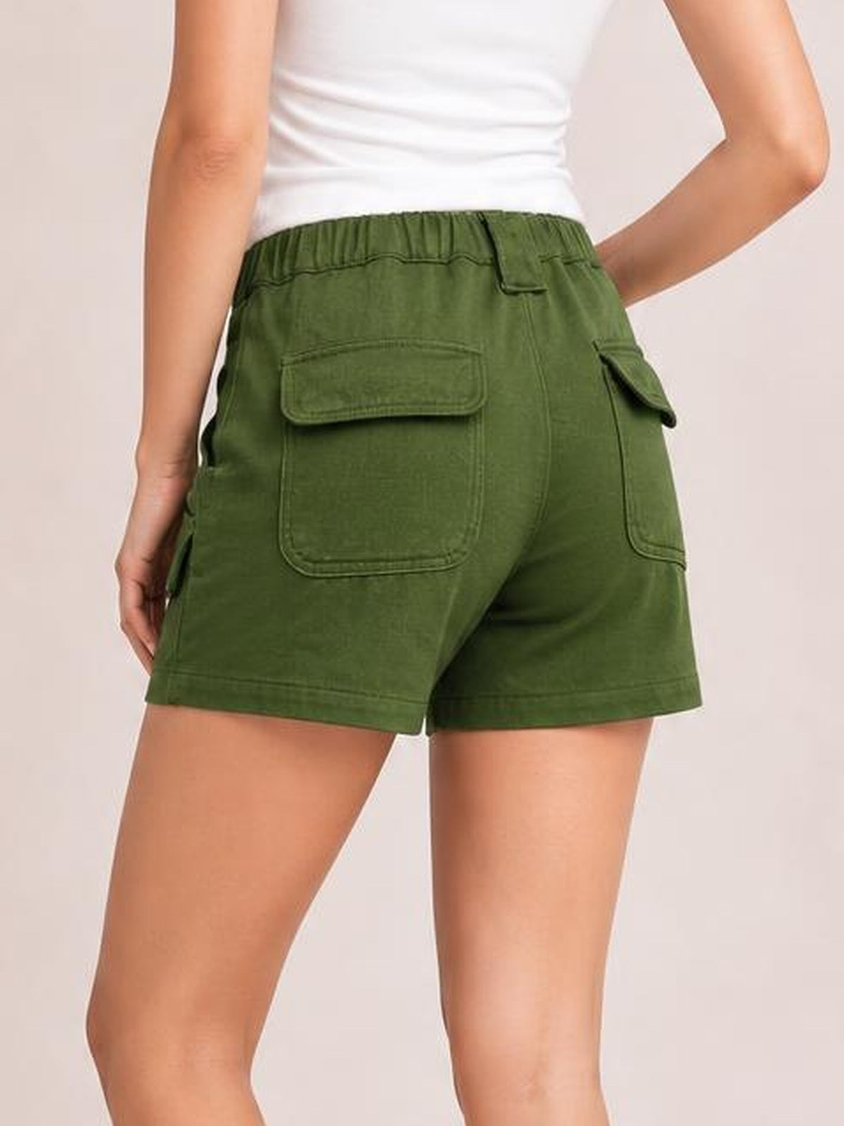 Model shown from behind wearing olive green high-waist shorts with an elastic waistband, relaxed fit, straight hems, and multiple flap cargo pockets.
