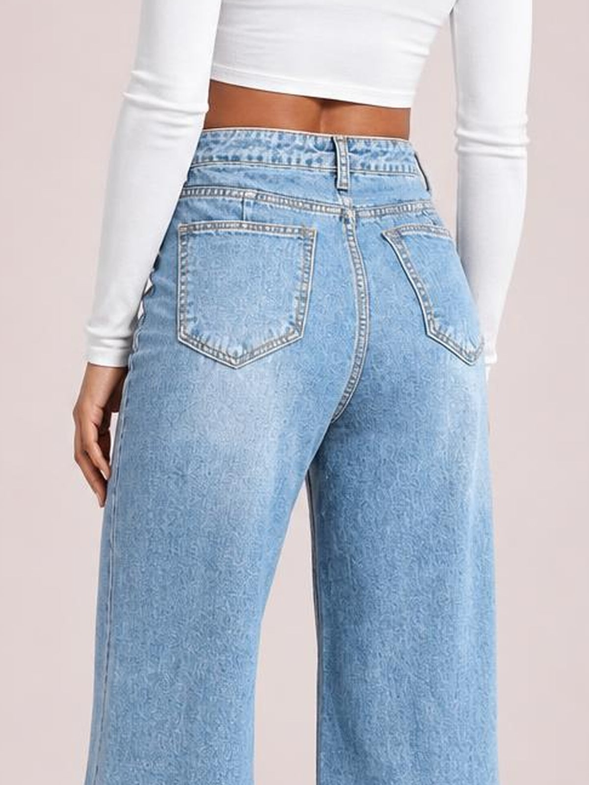 Model shown from behind wearing light blue high waist wide leg jeans with a structured waistband, belt loops, zip fly, and two back patch pockets.