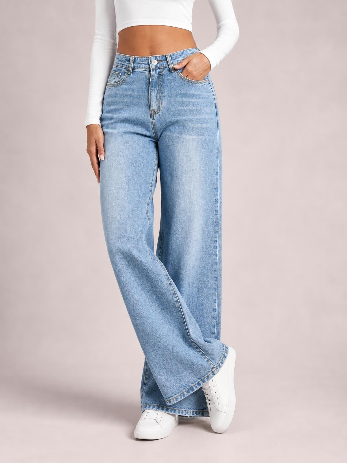 A model poses with one leg crossed in light blue high-waist wide-leg jeans featuring belt loops, a button closure, zip fly, and front pockets.