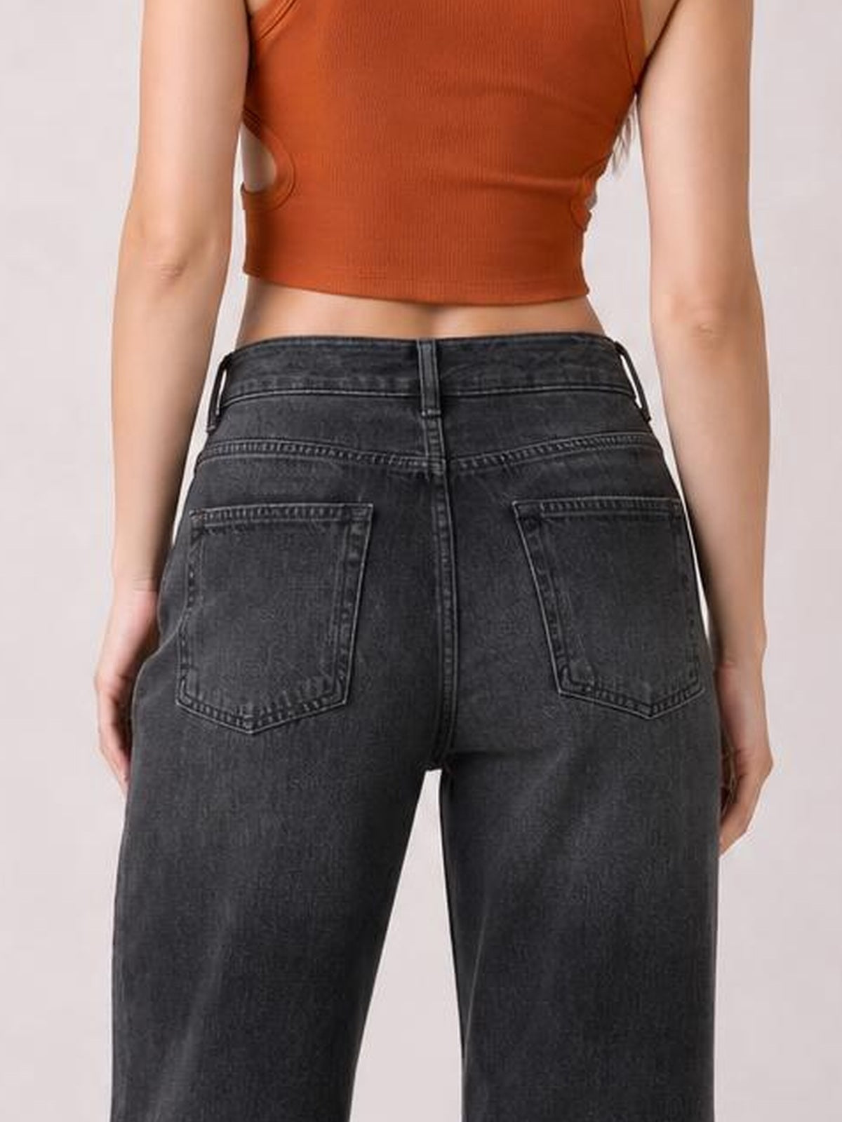 Model shown from behind in dark gray high-waist wide-leg jeans, standing with hands at her sides and displaying belt loops, seaming, and two back pockets.