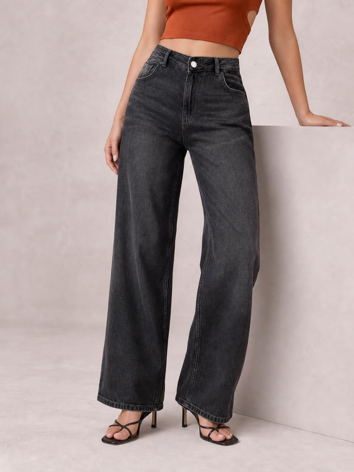 Model wearing dark gray high-waist wide-leg jeans with a button fly, belt loops, curved front pockets, and a relaxed full-length silhouette.