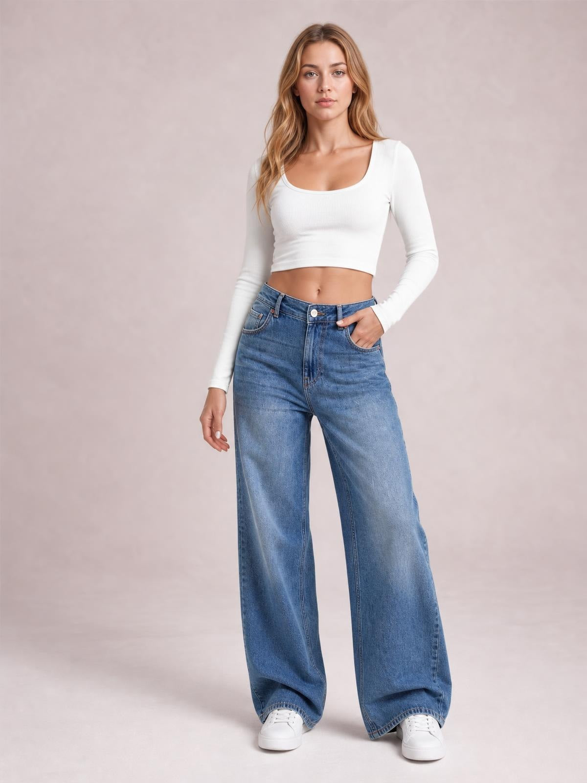 Model poses in blue high waist wide leg jeans with a button fly, front pockets, and a relaxed full-length silhouette.