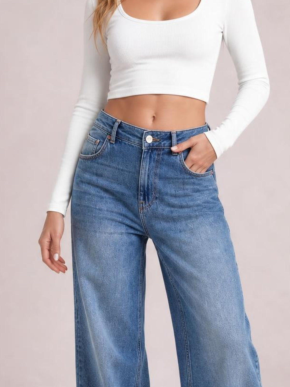 Model poses with one hand in the pocket of high-waist blue wide-leg jeans featuring a button closure, belt loops, front pockets, and structured seams.