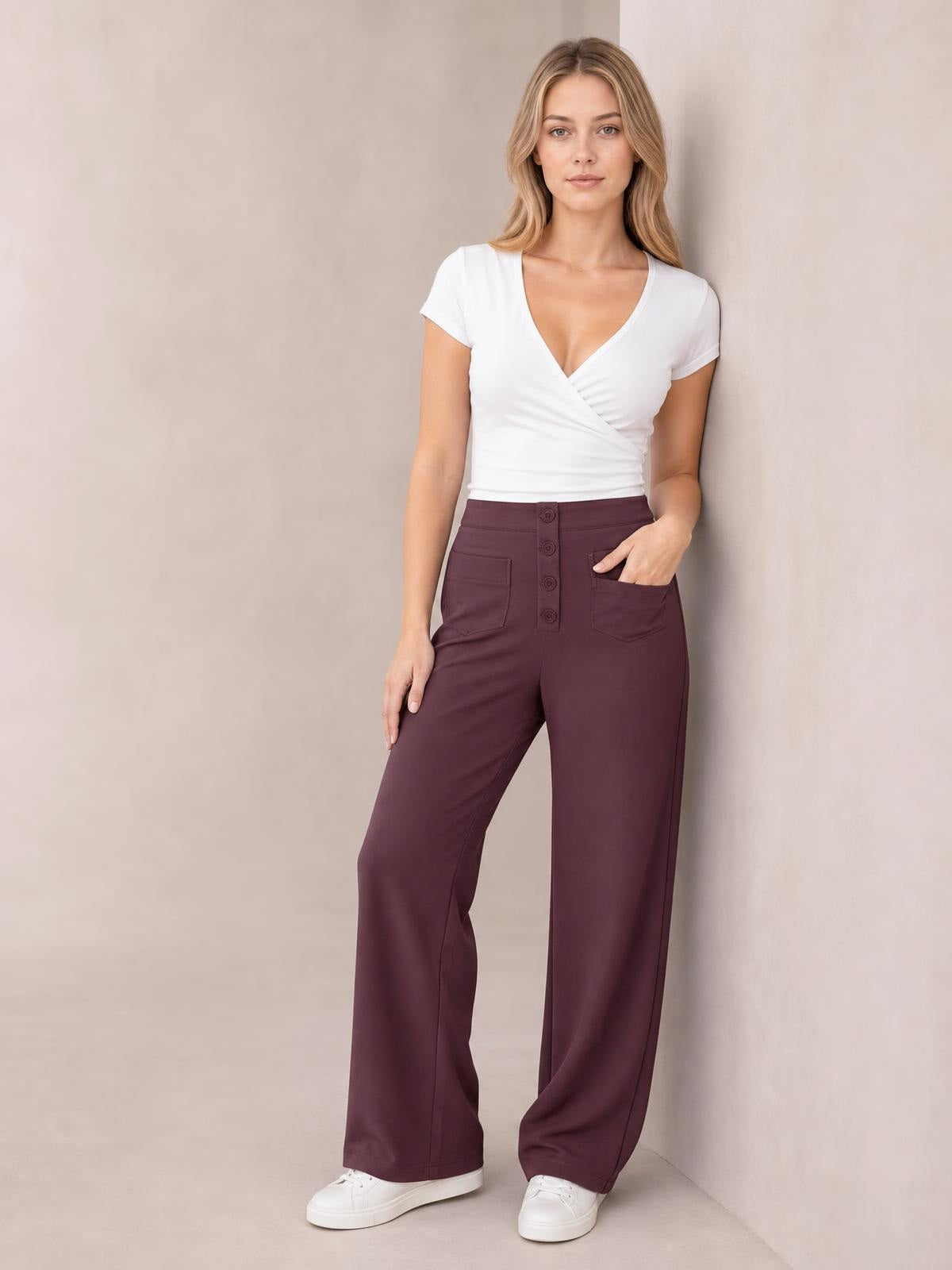 Model stands in burgundy high waist wide leg pants with front pockets, button fly, and a relaxed full-length silhouette.