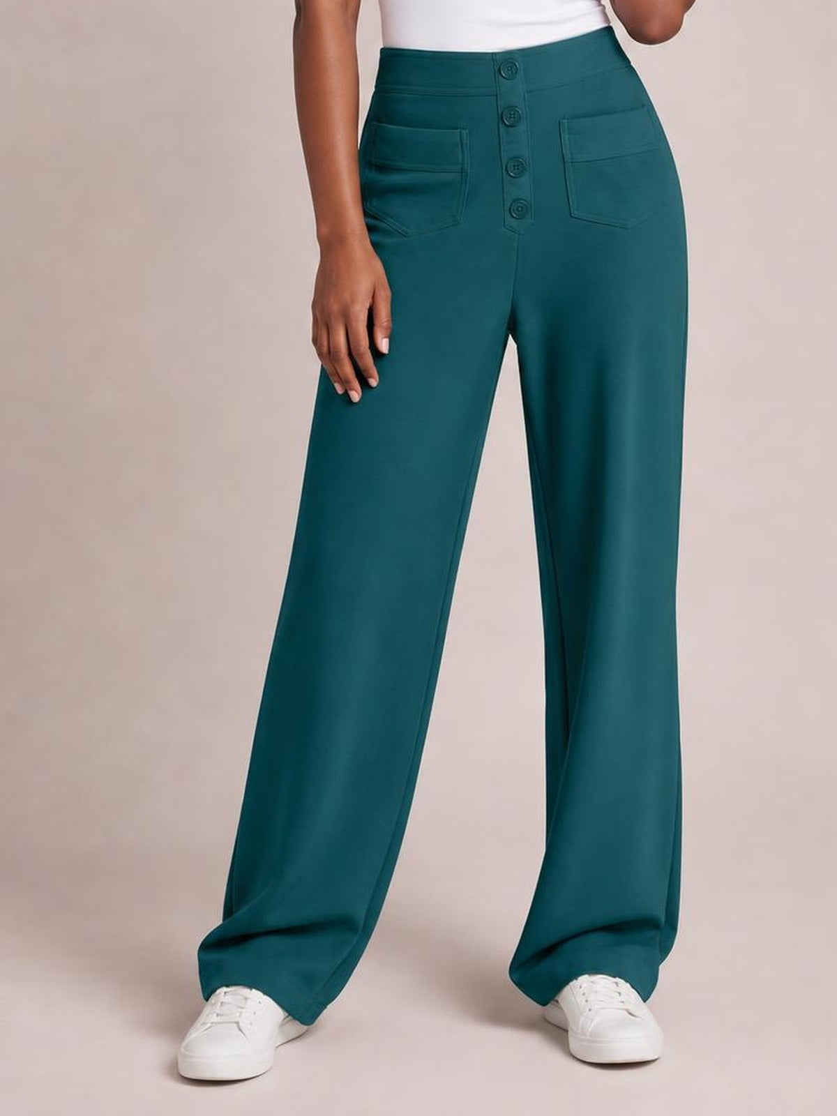 Model standing in teal high waist wide leg pants with front button closure, stitched pockets, and a relaxed full-length silhouette.