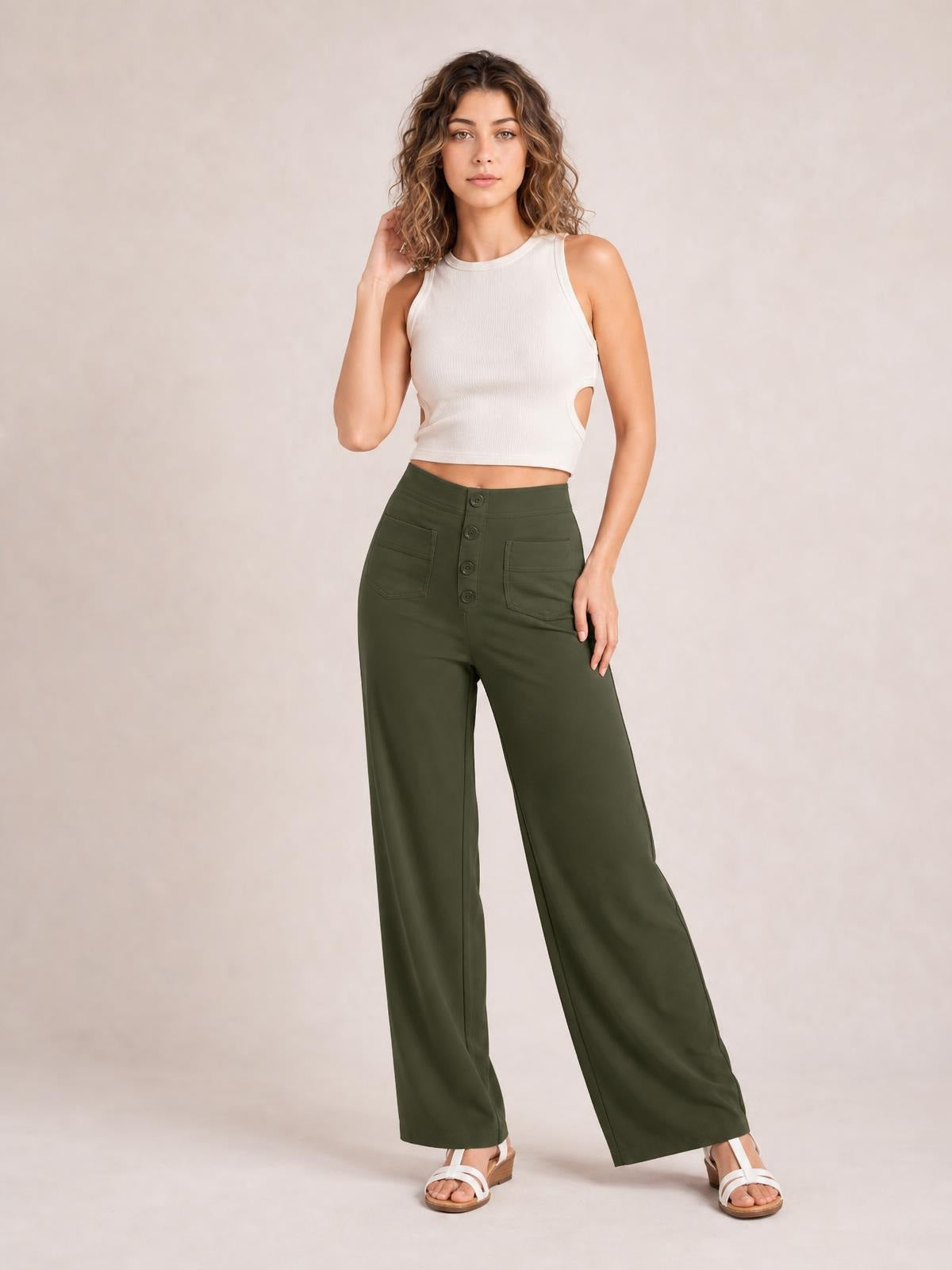 Model poses in olive green high waist wide leg pants with front pockets, button-front construction, and a flowing full-length silhouette.