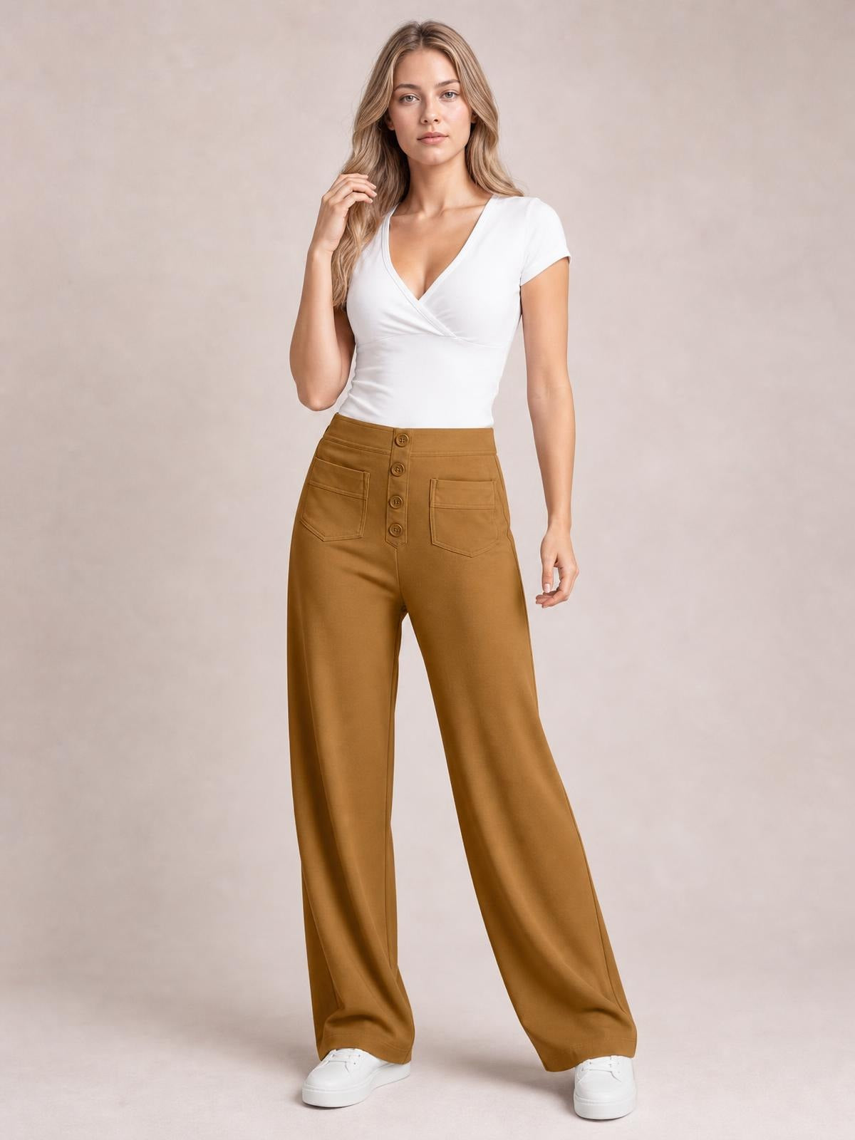 Model poses in caramel brown high waist wide leg pants with front button closure, patch pockets, and a relaxed full-length silhouette.