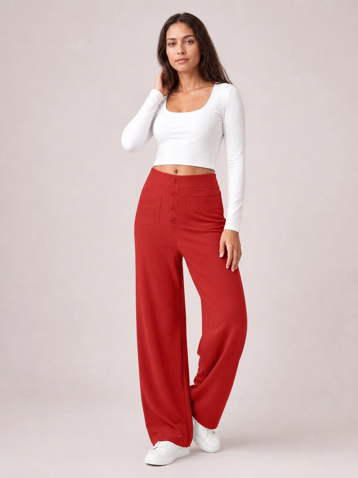 A model poses in red high-waist wide-leg pants with front buttons and patch pockets, standing with one leg crossed and paired with a fitted white top.