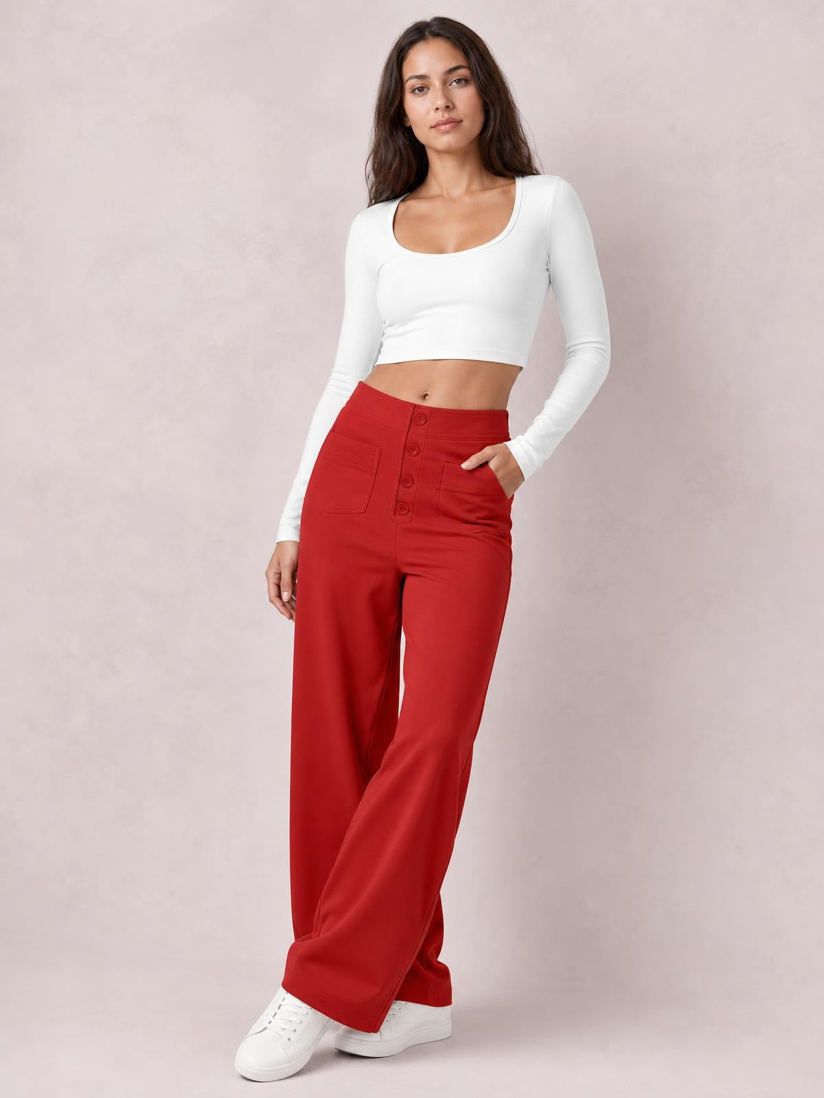Model poses in red high-waist wide-leg pants with front pockets and button closure, paired with a fitted white long-sleeve cropped top.