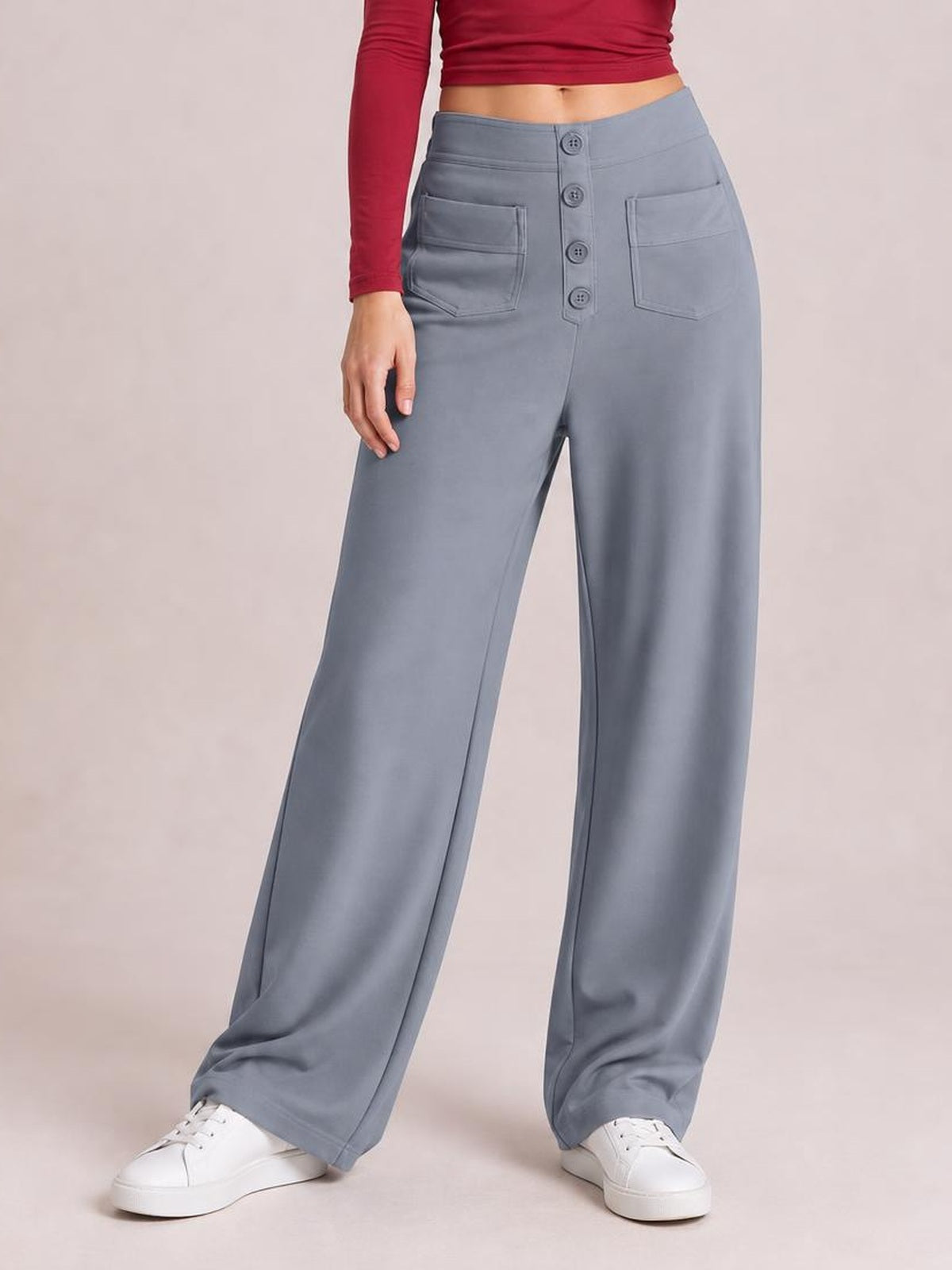 Model wearing gray high waist wide leg pants with front button closure, patch pockets, and a relaxed full-length silhouette.