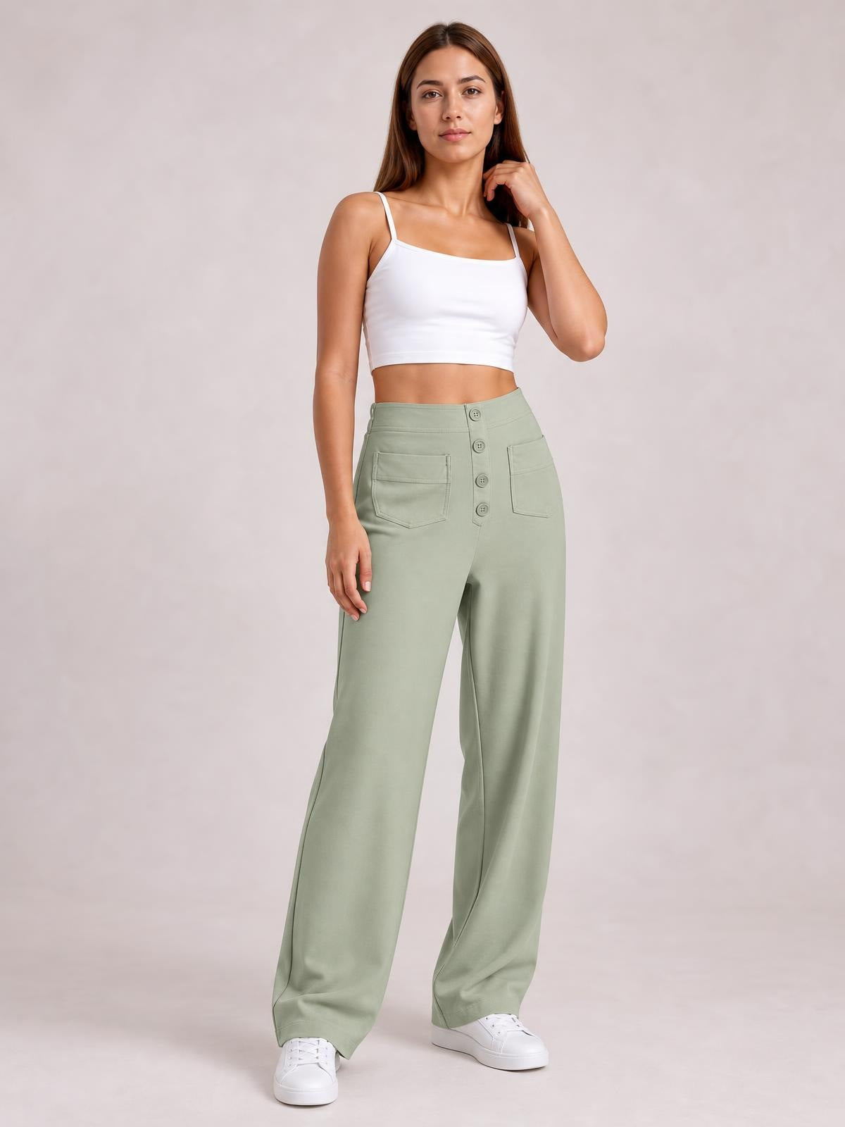 A model stands in sage green high-waist wide-leg pants with front pockets, button closure, and a relaxed floor-length silhouette, paired with a white crop top.