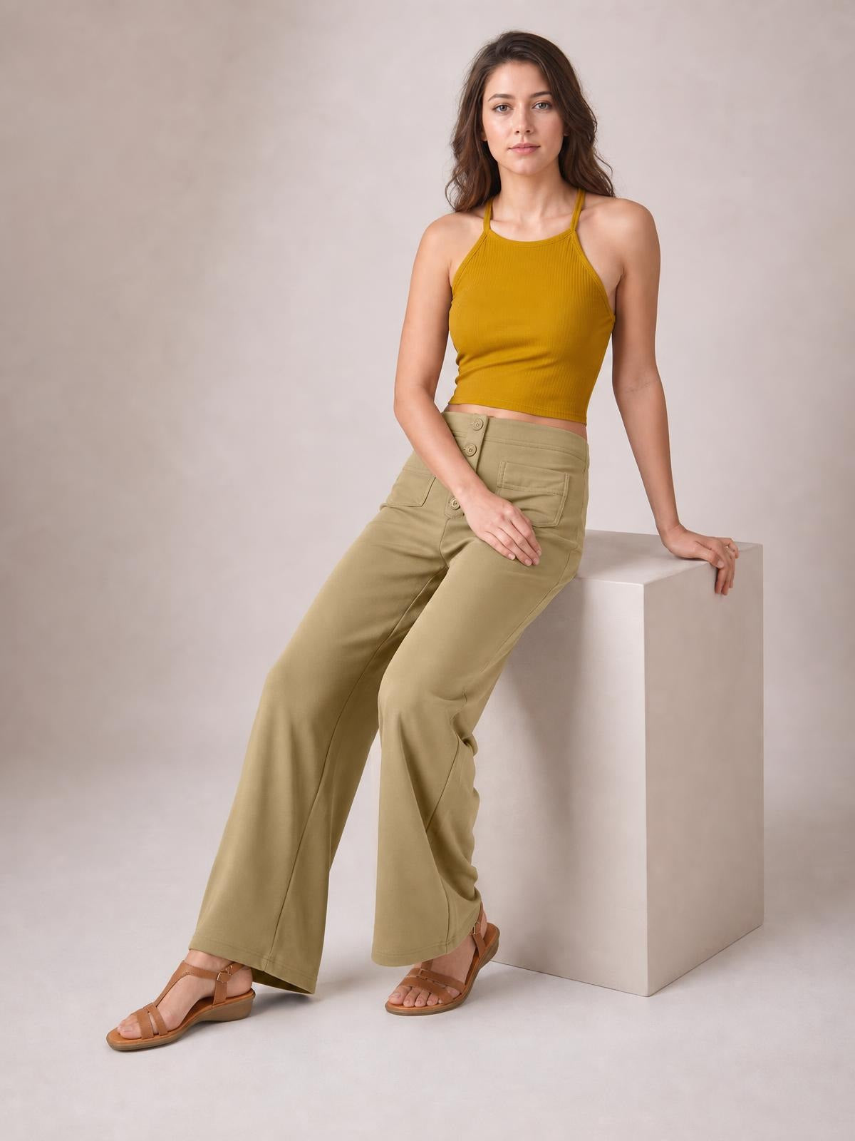 Model seated in tan high waist wide leg pants with front pockets, buttoned waistband, and a relaxed full-length silhouette.