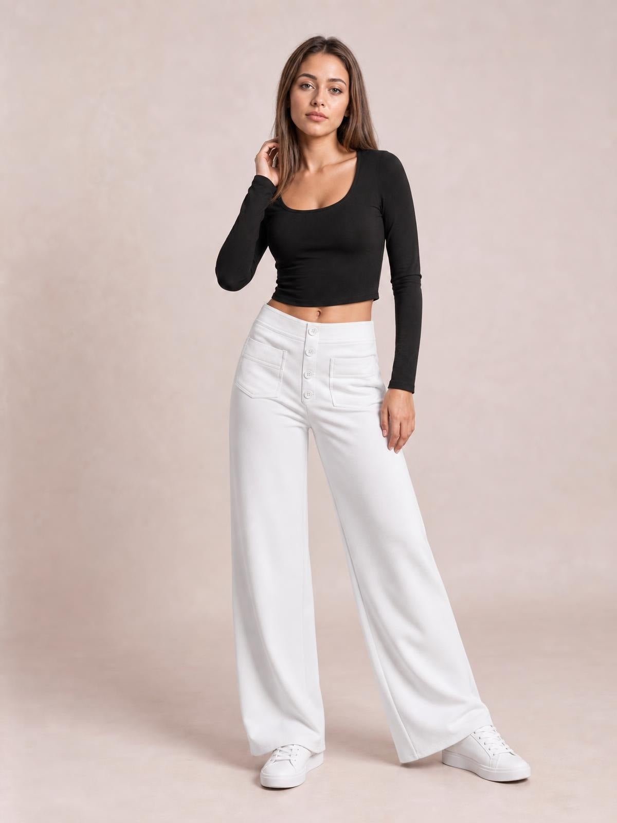 Model poses in white high waist wide leg pants with front pockets and button-fly detailing, paired with a fitted black long-sleeve top.