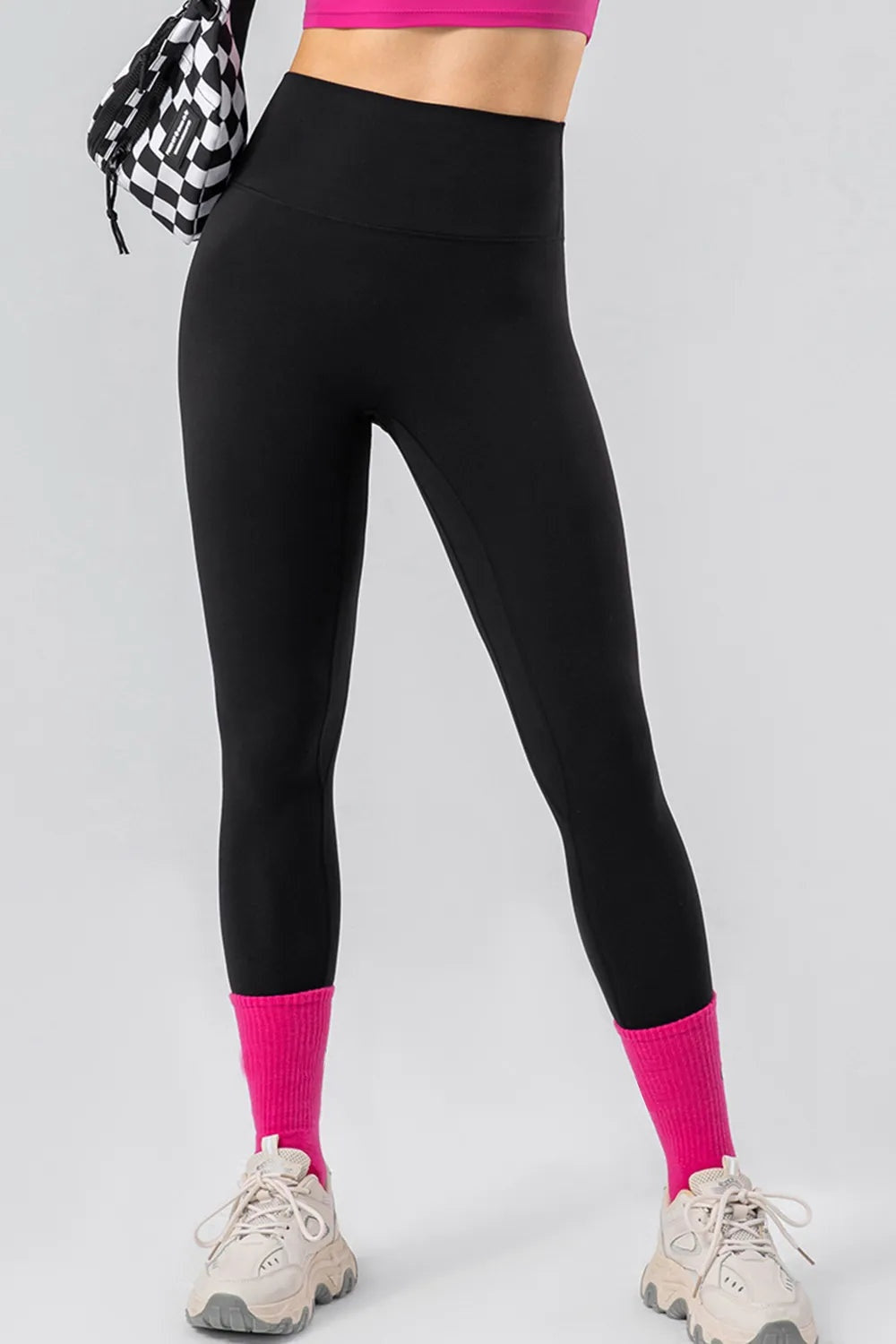 Model stands with legs apart wearing black high-waist active leggings with a wide waistband, smooth stretch fabric, close-fitting silhouette, and full-length legs.