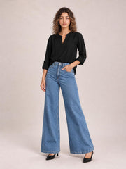 Model poses in light blue high-waisted bootcut jeans with front pockets, belt loops, a button fly, and a wide-leg silhouette.