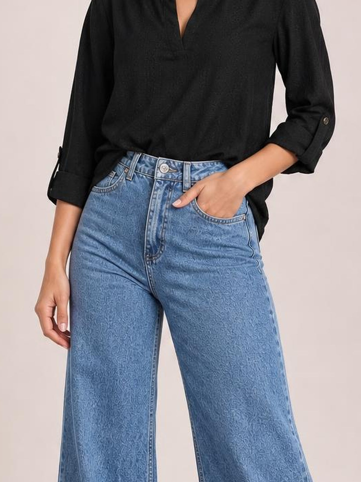 Model wearing light blue high-waisted bootcut jeans with belt loops, front pockets, button closure, and a slightly stretchy denim construction.