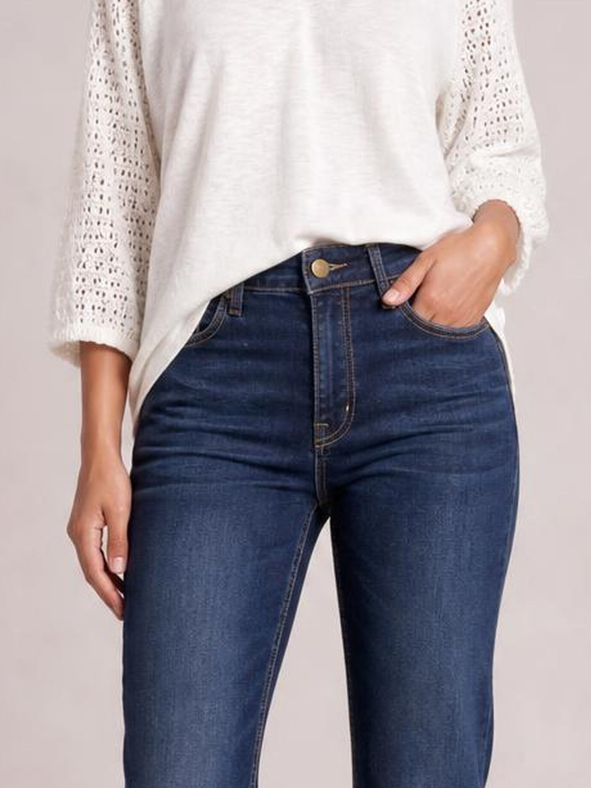 Model wearing dark blue high-waisted bootcut jeans with a button fly, belt loops, front pockets, and a fitted silhouette through the hips and thighs.