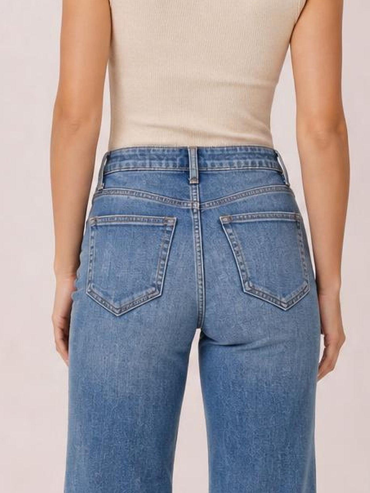 Model shown from behind wearing blue high-waisted flare leg jeans with a fitted seat, buttoned waistband, belt loops, center seam, and two back pockets.