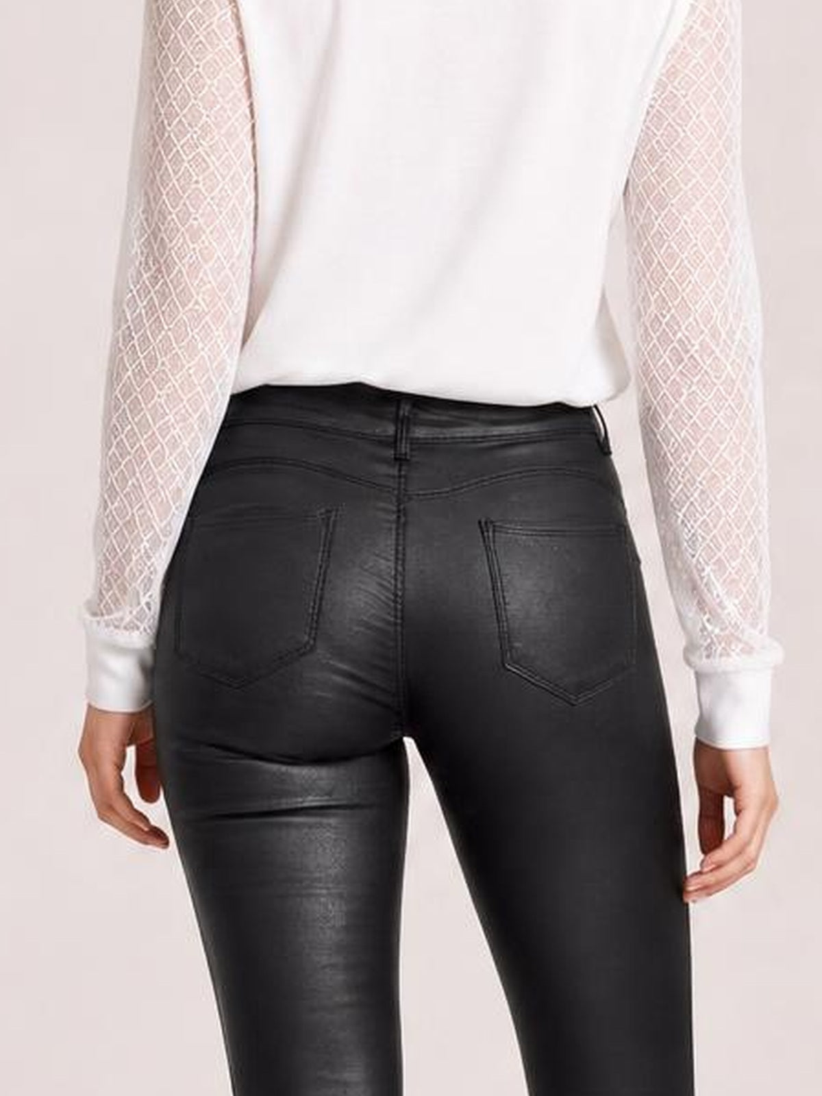 Model shown from behind wearing black high-waisted faux leather skinny pants with stitched belt loops, back pockets, and a close-fitting silhouette.