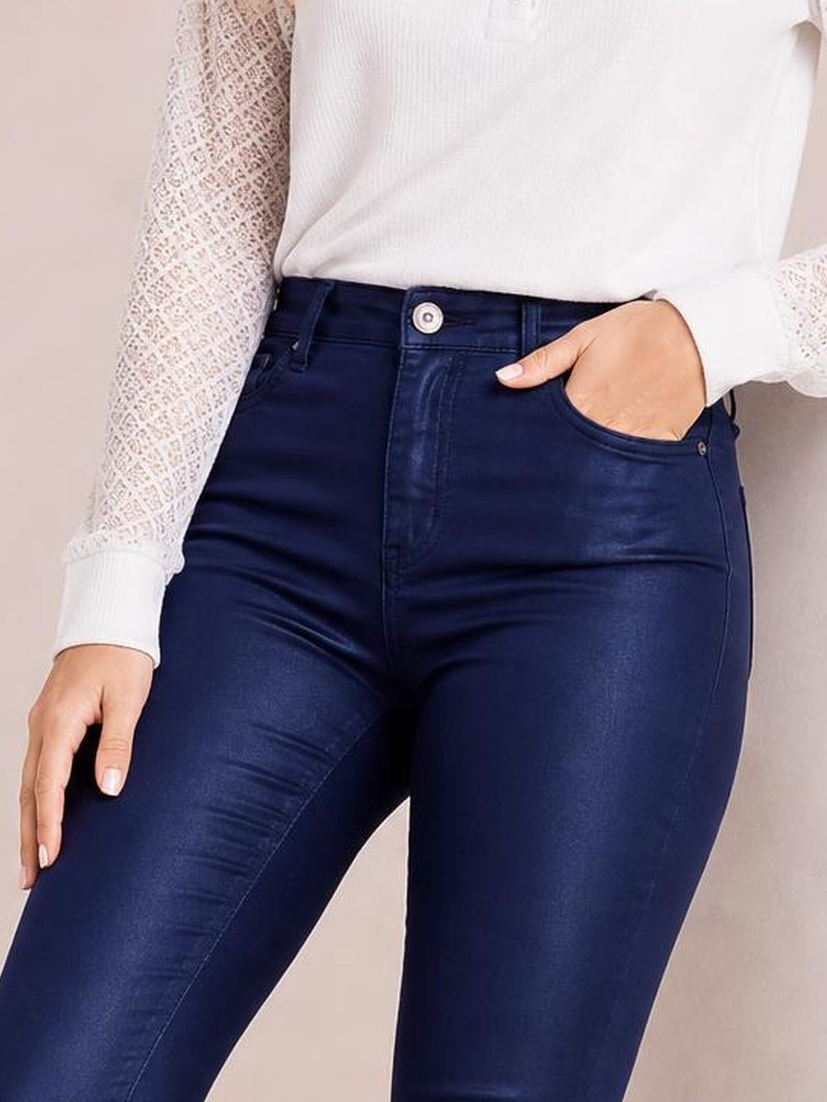 A model wears dark navy high-waisted faux leather skinny pants with belt loops, a button closure, front pockets, and a sleek fitted silhouette.