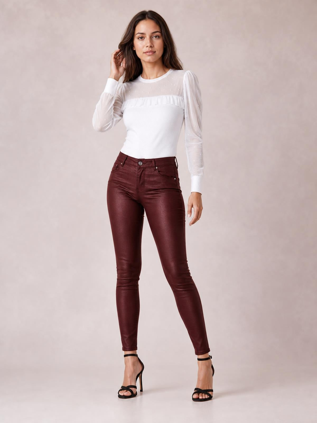 Model poses in burgundy high-waisted faux leather skinny pants with front pockets, belt loops, button closure, and a sleek ankle-length silhouette.