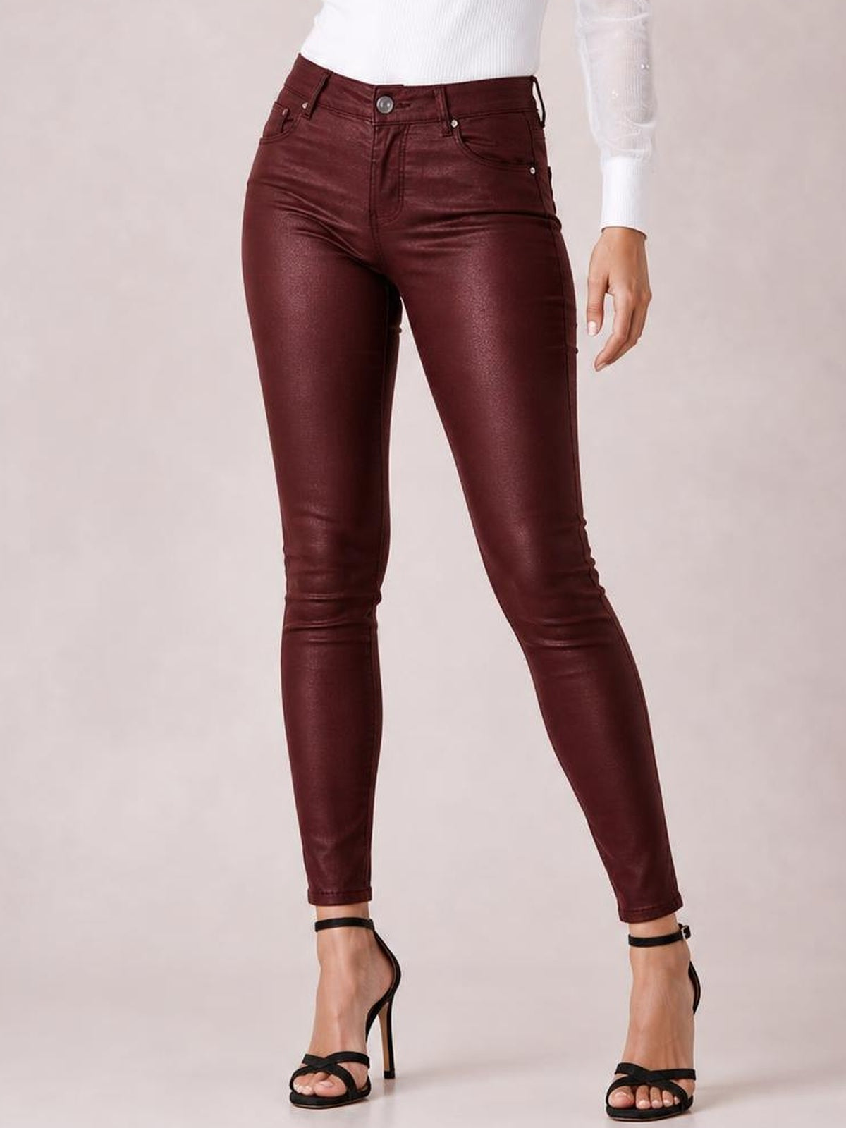 Model poses in burgundy high-waisted faux leather skinny pants with front pockets, belt loops, button closure, and a sleek ankle-length silhouette.