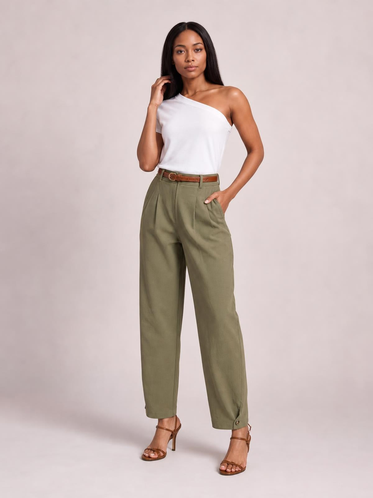 Model wearing olive green high-waisted pleated pants with a relaxed tapered silhouette, belt loops, side pockets, and buttoned ankle cuffs.