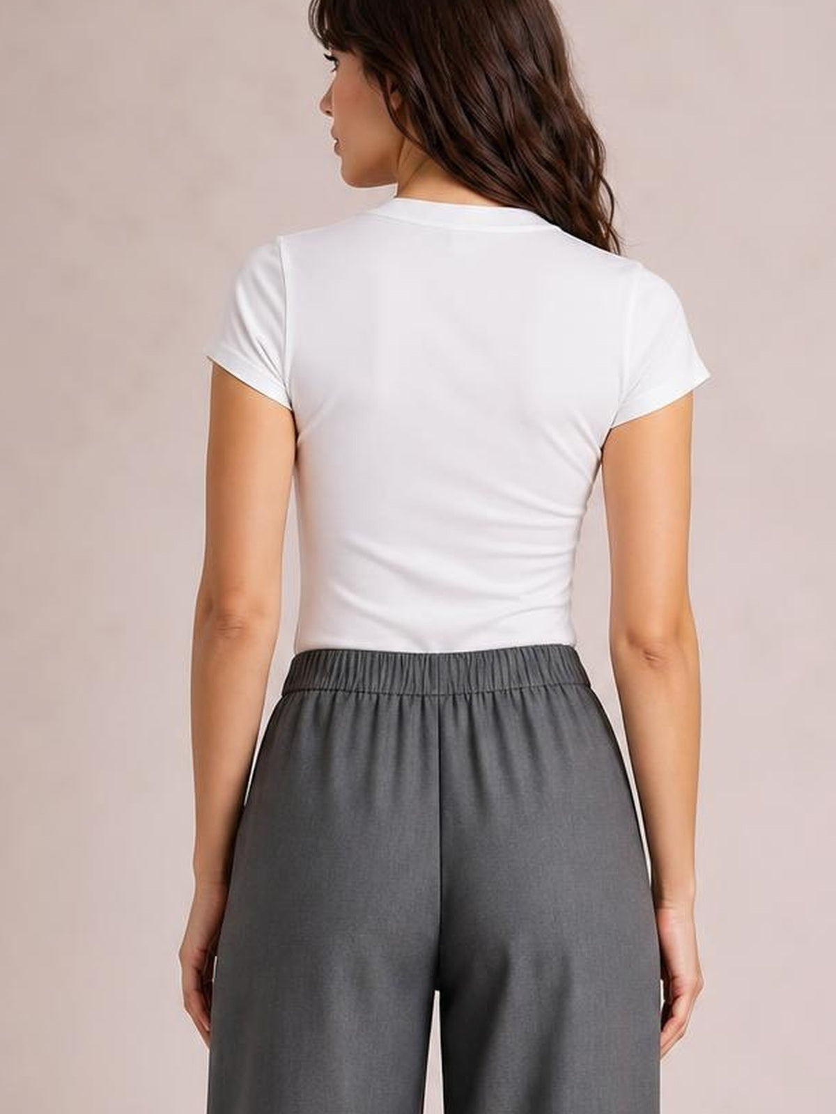 Back view of a model wearing gray high-waisted wide-leg pants with a structured waistband and relaxed, flowing silhouette.