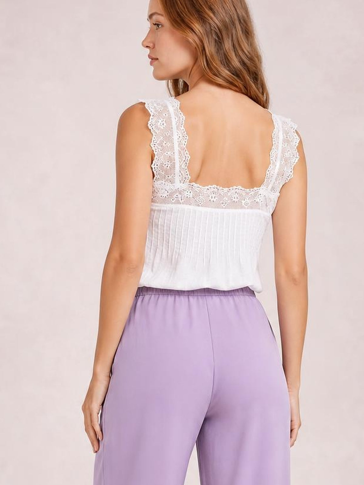 Model shown from behind wears lavender high-waisted wide-leg pants with a smooth waistband and center-back seam, paired with a white lace-trim camisole.