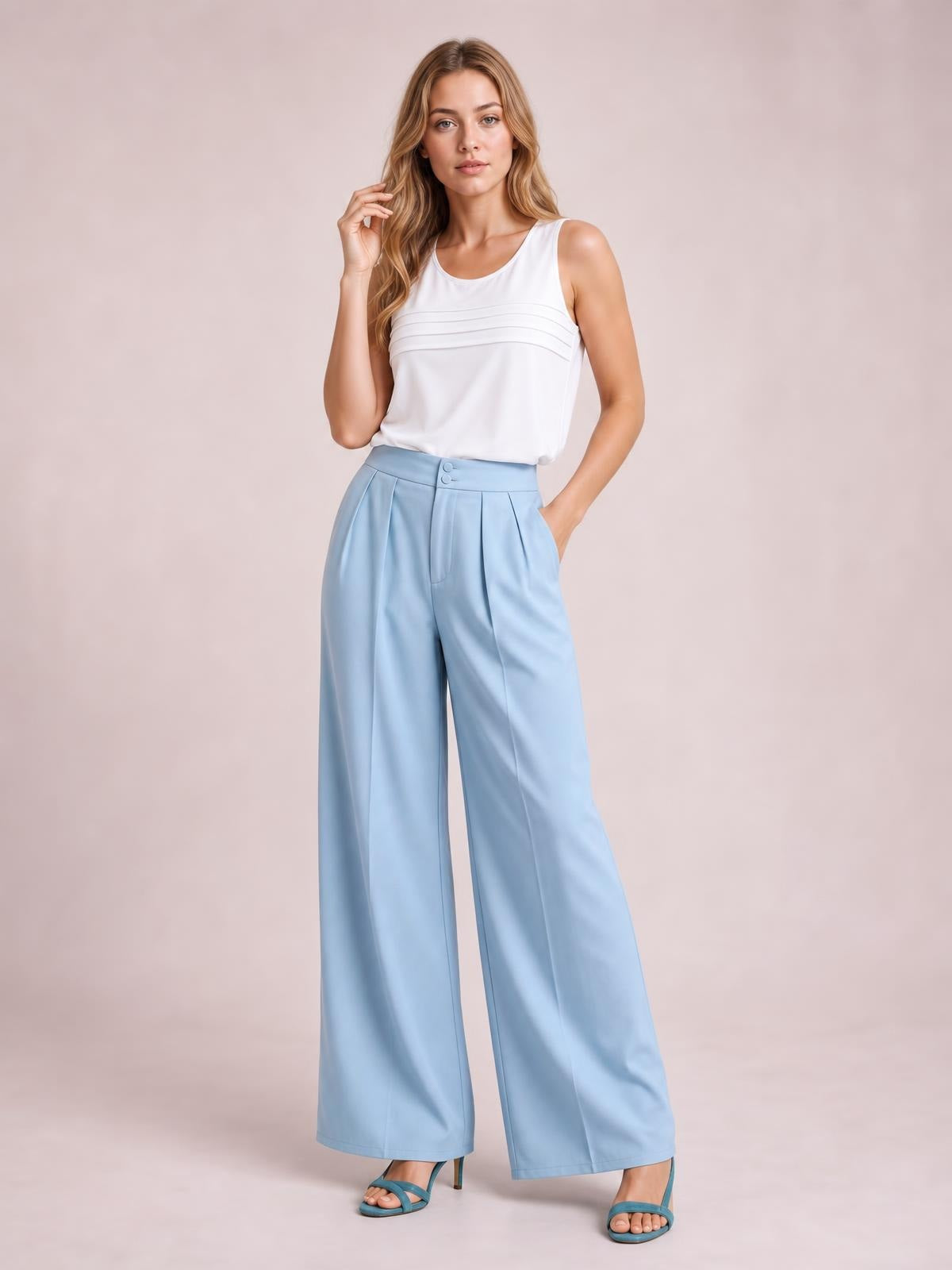 A model poses in light blue high-waisted pleated wide-leg pants with buttoned front closure, side pockets, and a flowing full-length silhouette.