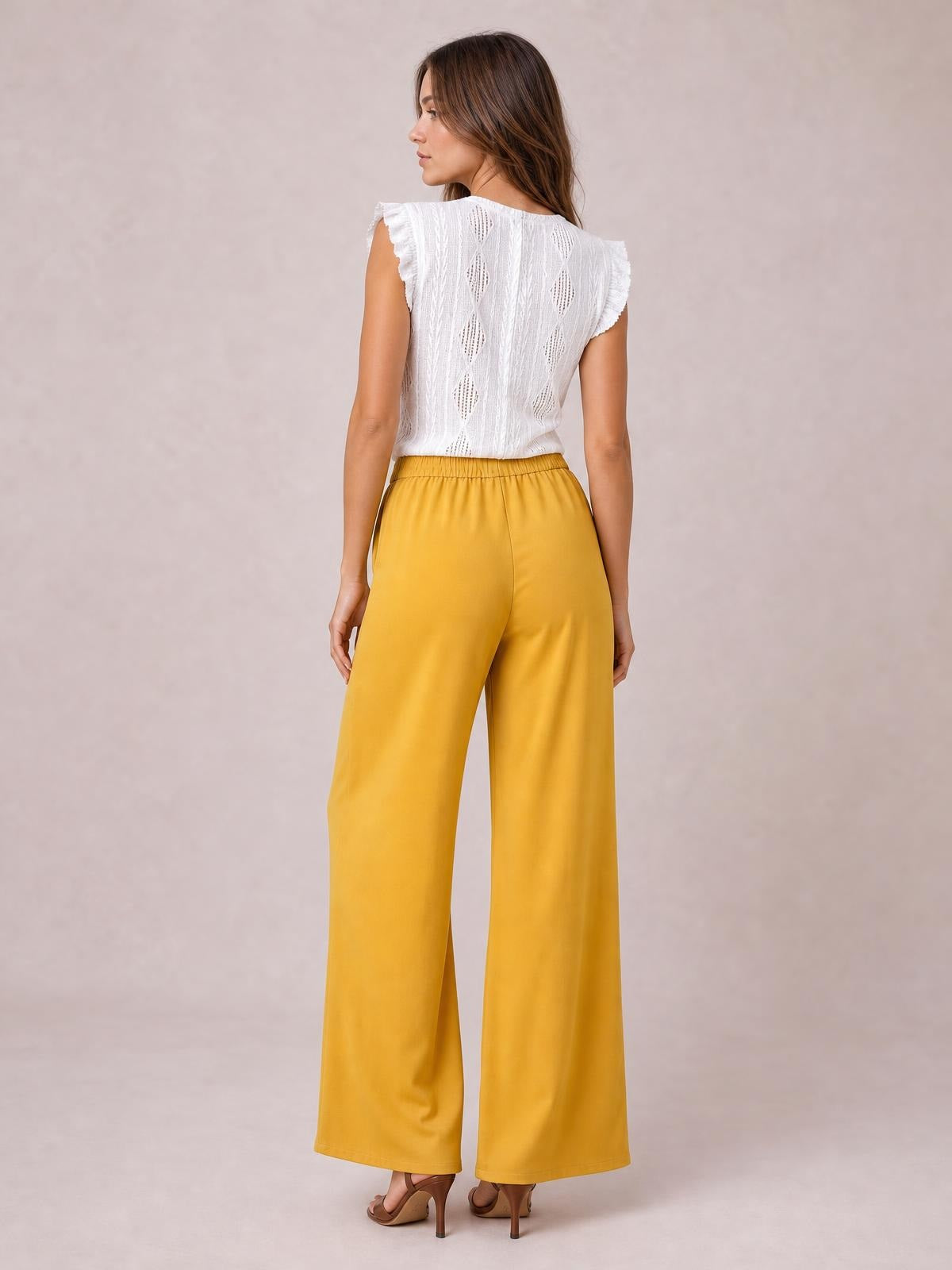 Model shown from behind wears mustard-yellow high-waisted wide-leg pants with a smooth, flowing silhouette and full-length hems.