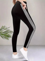 A model poses in black high-waisted active leggings with a fitted ankle-length silhouette, visible seam detail, and a bold white houndstooth side panel.
