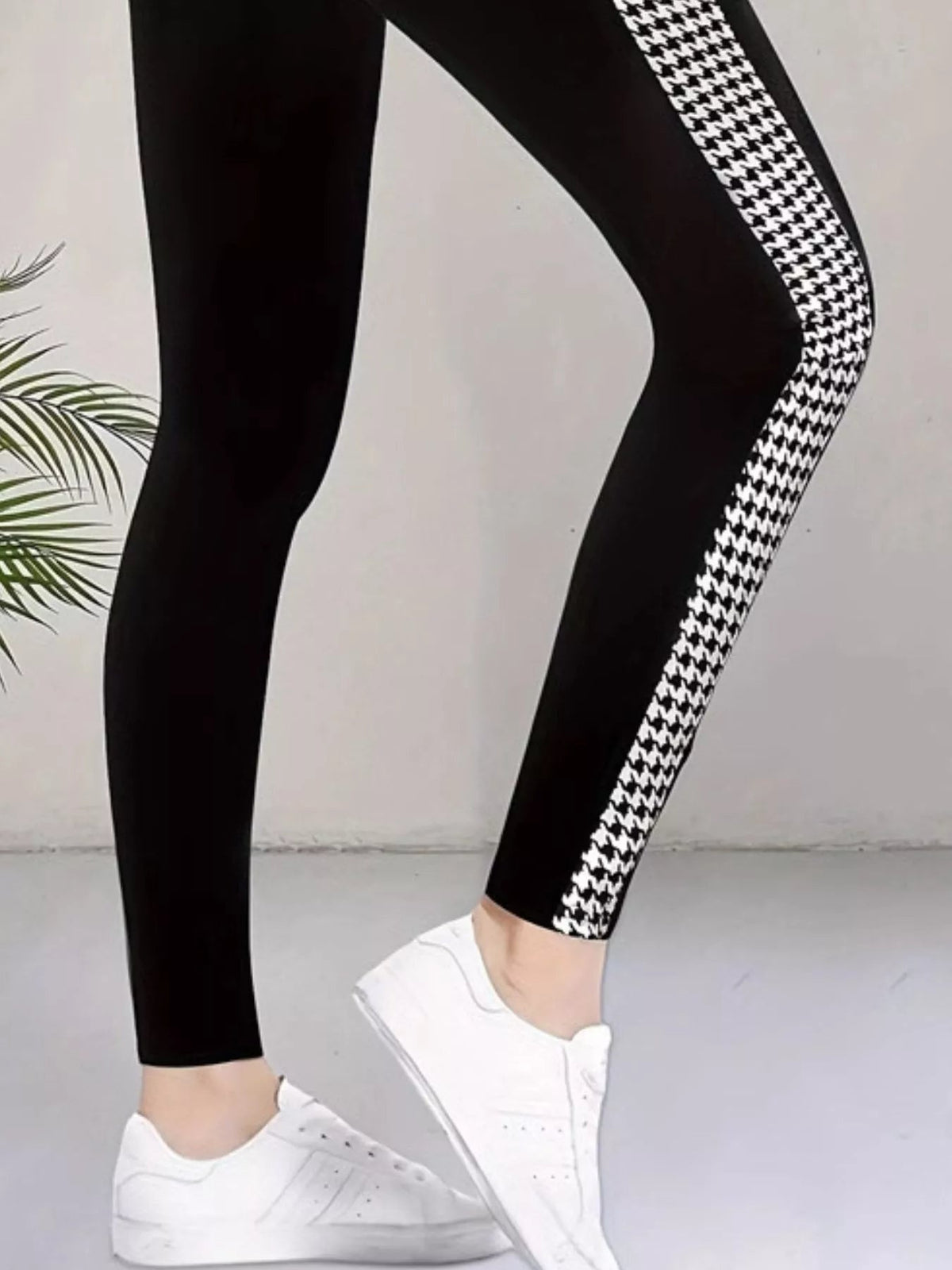 Model’s legs in black high-waisted active leggings feature a white houndstooth side panel, sleek fitted silhouette, and visible seam detail.