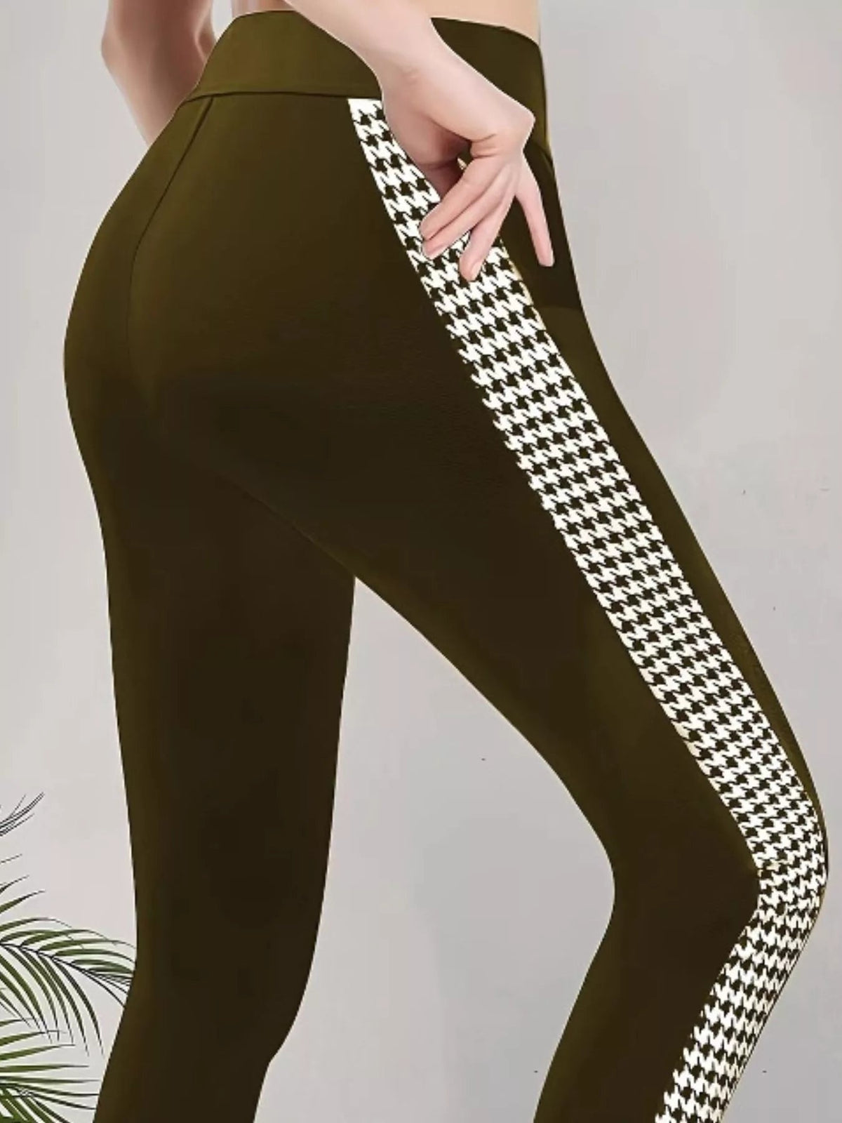 Model wears high-waisted dark olive active leggings with a slim silhouette, seam detailing, and a bold black-and-white houndstooth side panel, hand resting on hip.