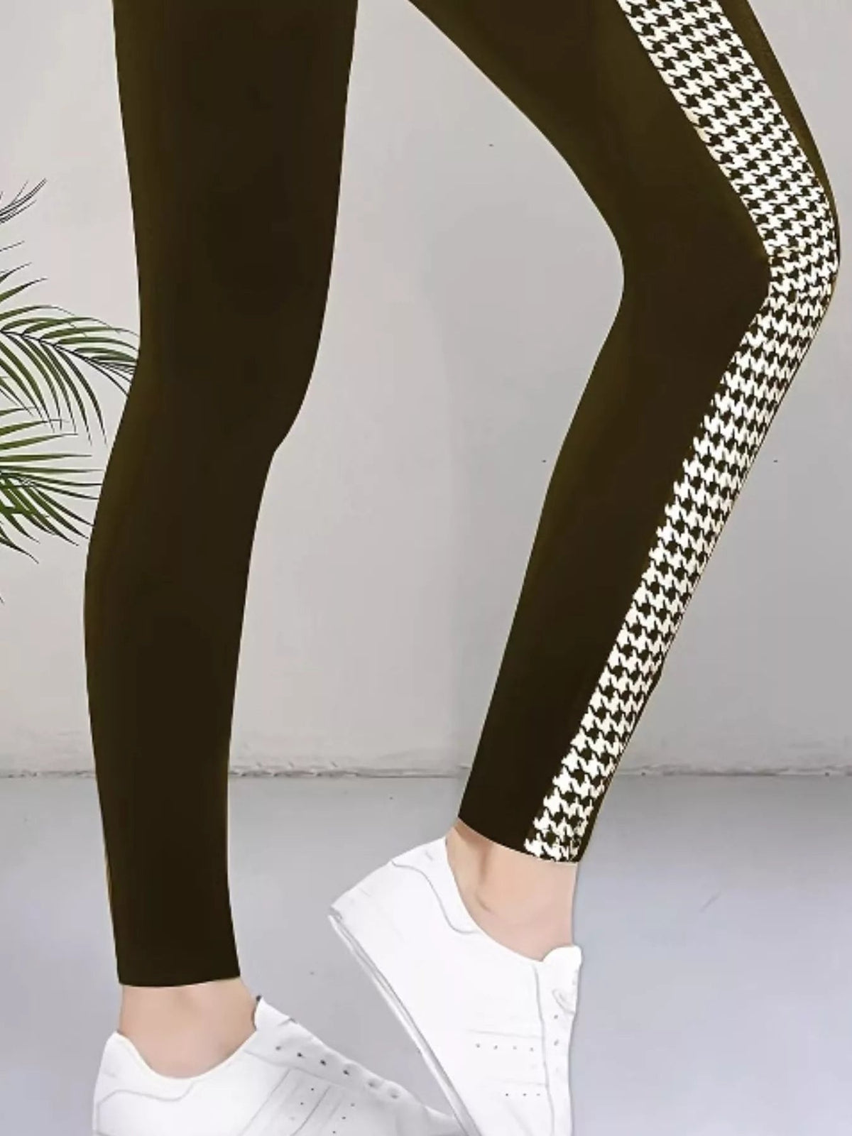 Model wears high-waisted dark active leggings with a bold white houndstooth side panel, stretch fit, seam detail, and tapered ankle silhouette.