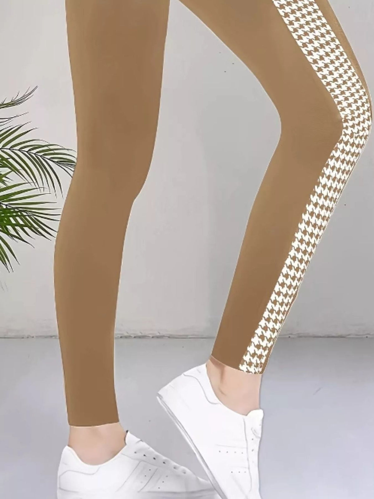 Close-up of a model wearing tan high-waisted active leggings with a white side houndstooth panel, slim ankle-length silhouette, and visible seam detail.