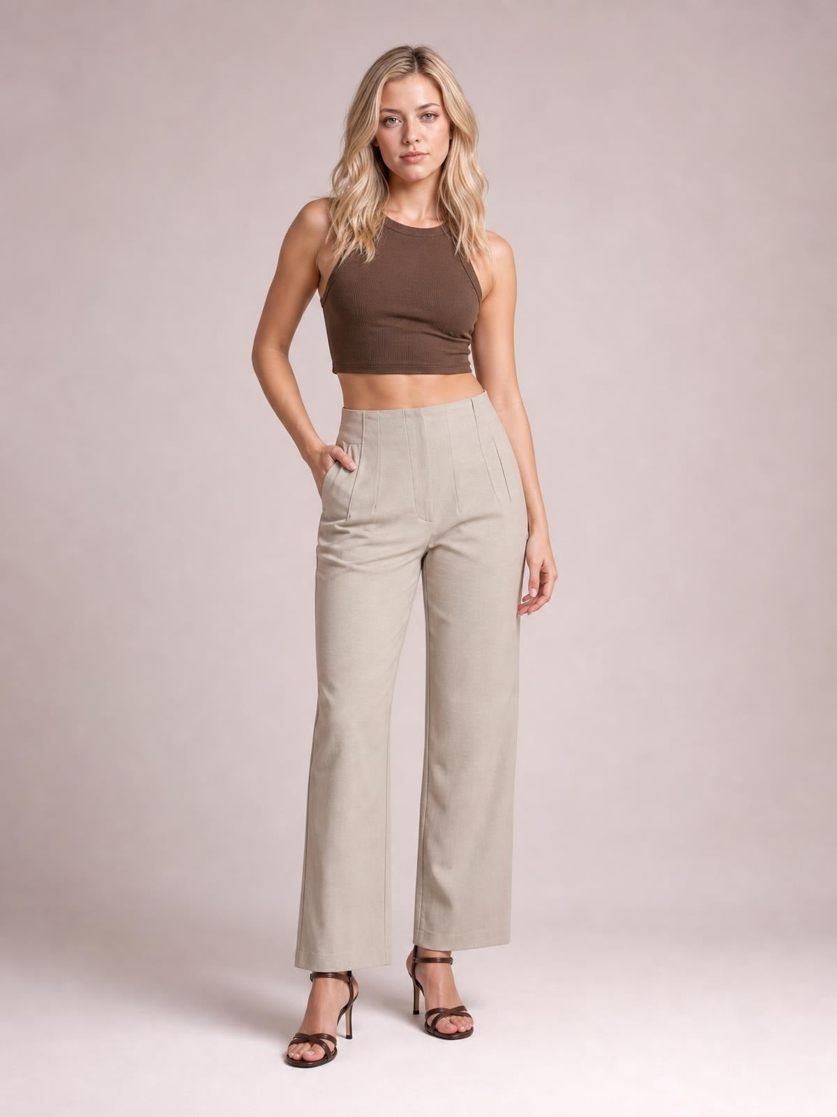 Model poses in beige high-waisted straight-leg pants with front pockets, visible seam detailing, a relaxed silhouette, and cropped hems.