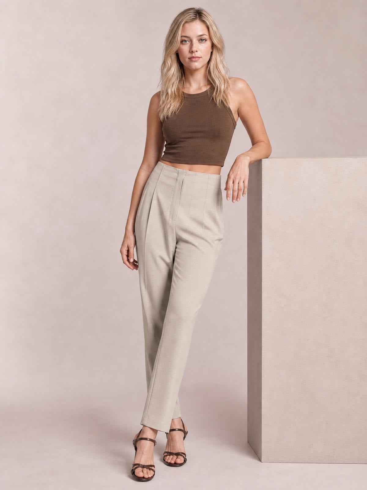 Model poses in light beige high-waisted straight-leg pants with front pleats, side pockets, and a tailored silhouette.