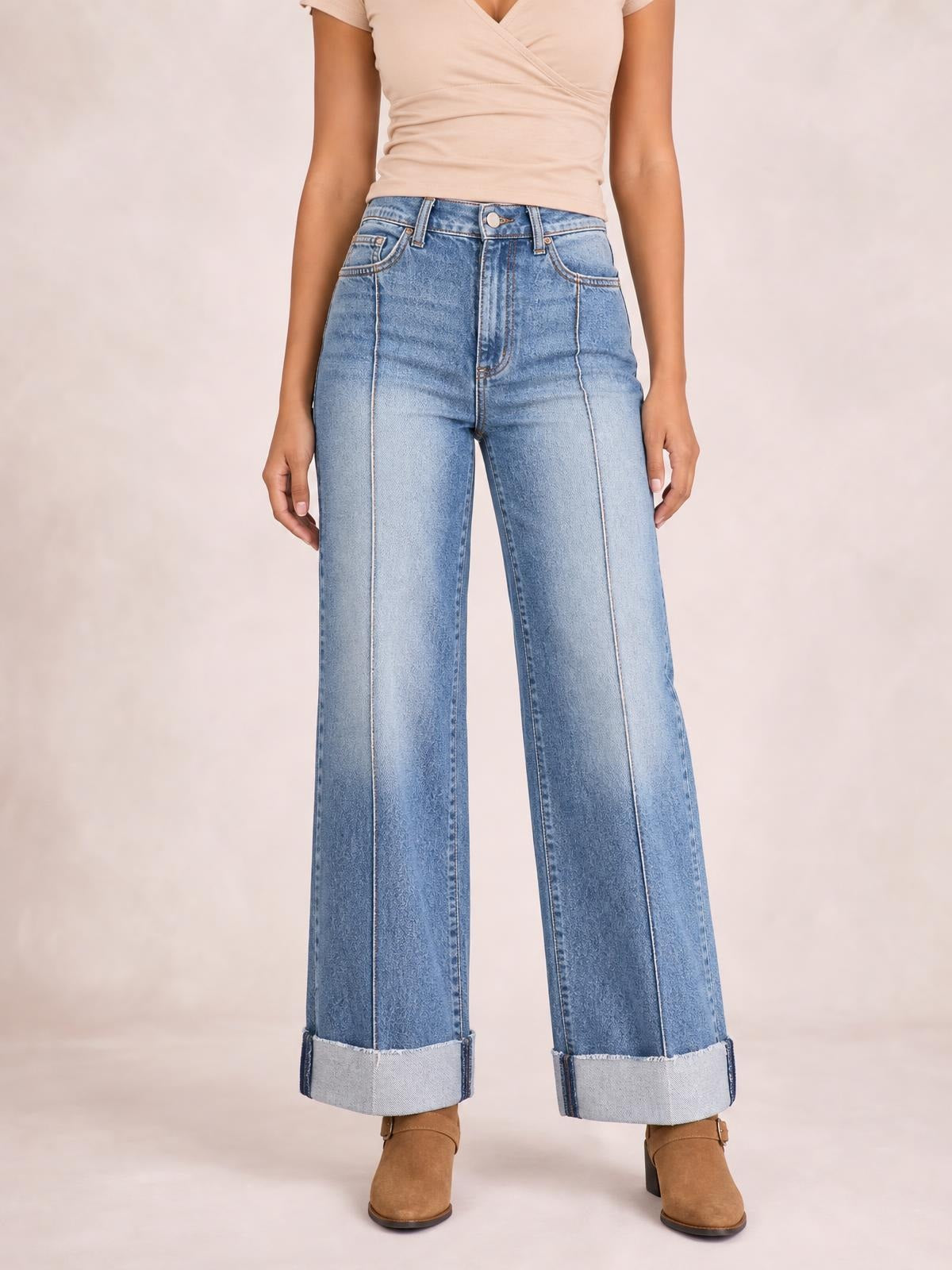 Model wears light blue high-waisted wide-leg cuffed jeans with contrast stitching, front pockets, a button fly, and oversized rolled cuffs.