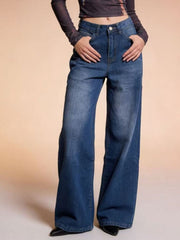 Model wears dark blue high-waisted wide leg jeans with front pockets, belt loops, button closure, and a relaxed full-length silhouette.
