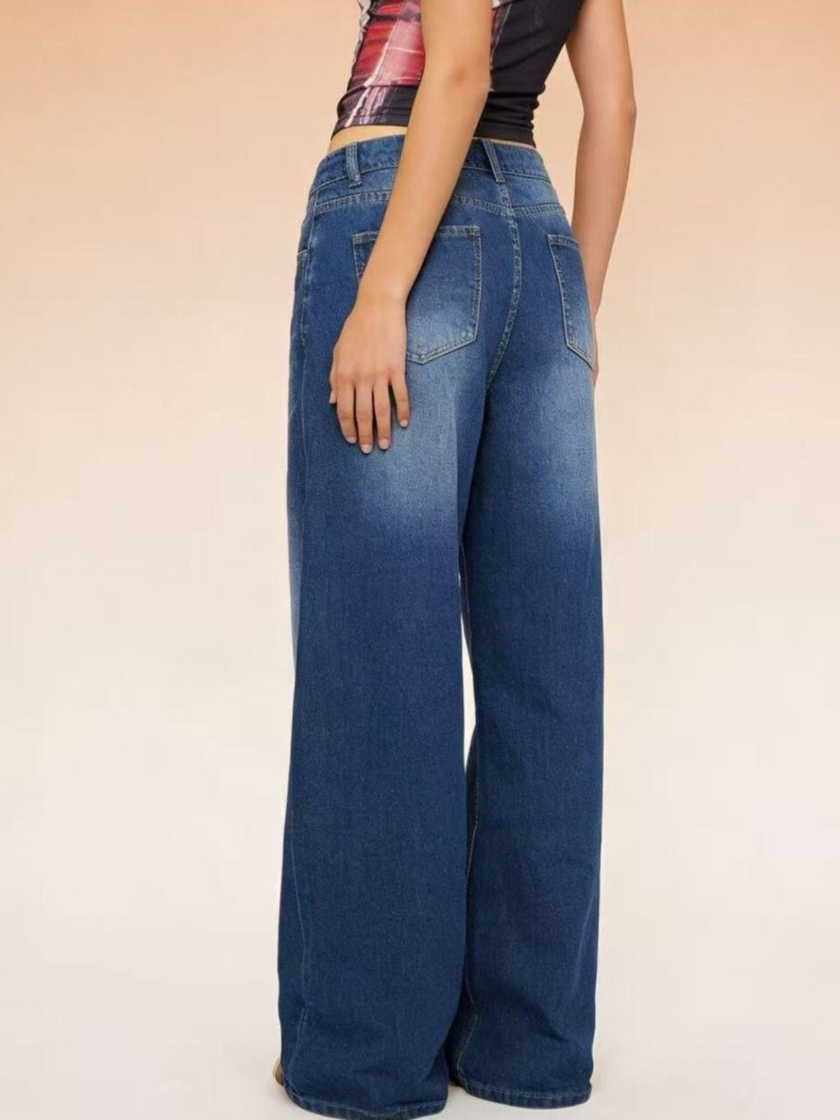 Model posed from the back in dark blue high-waisted wide-leg jeans with belt loops, rear patch pockets, and a relaxed full-length silhouette.