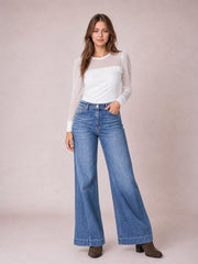 Model poses with one hand in the pocket of light-wash high-waisted wide leg jeans, featuring a relaxed silhouette, front fly, belt loops, and five-pocket construction.