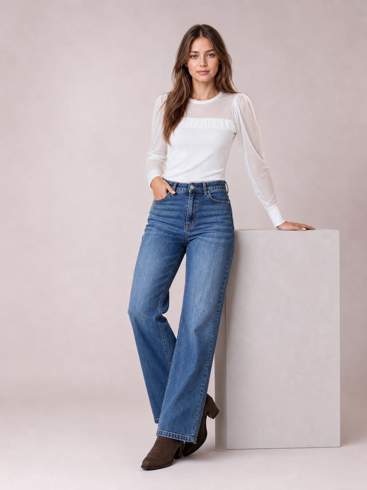 A model poses in washed blue high-waisted wide leg jeans with a button-fly waistband, belt loops, front pockets, and a relaxed full-length silhouette.