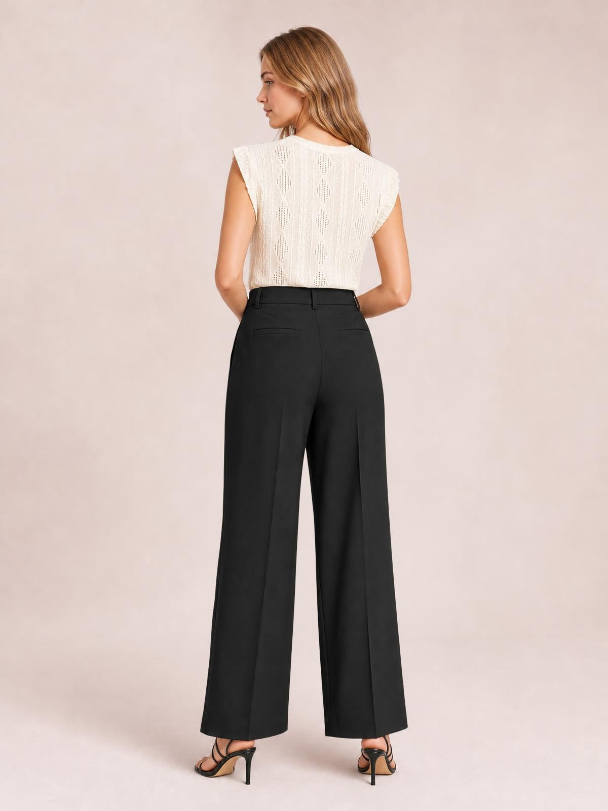 Model poses from the back in black high-waisted wide-leg pants with belt loops, button closure, back welt pockets, and a flowing full-length silhouette.
