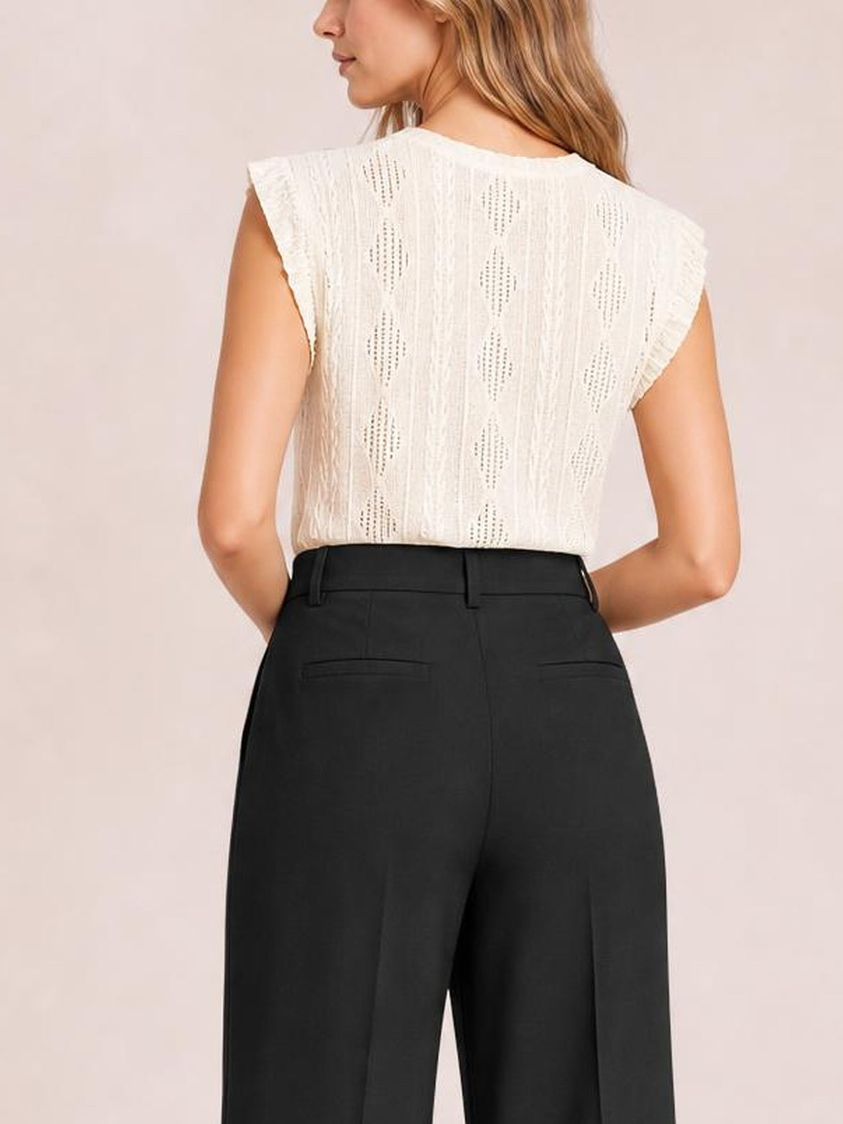A model poses from the back in black high-waisted wide-leg pants with belt loops, tailored seams, and two welt back pockets.