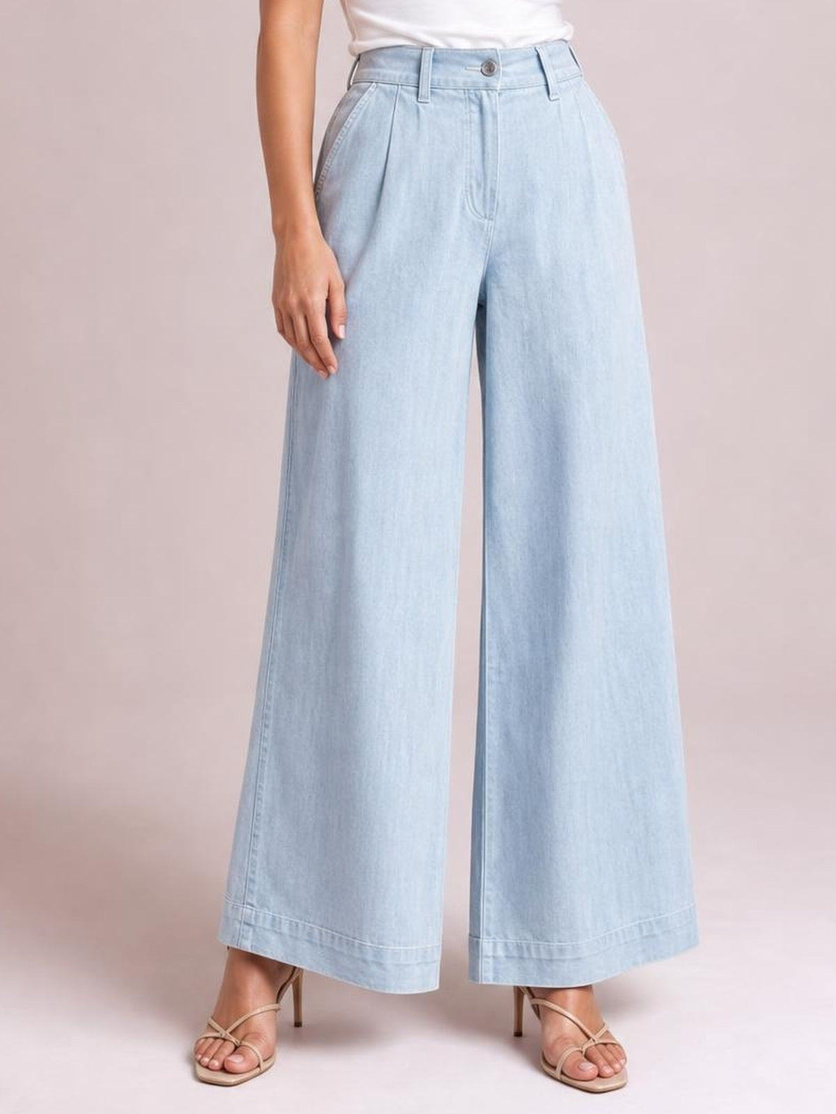 Model wearing light blue high-waisted wide-leg pants with a button closure, belt loops, angled pockets, front pleats, and wide cropped hems.